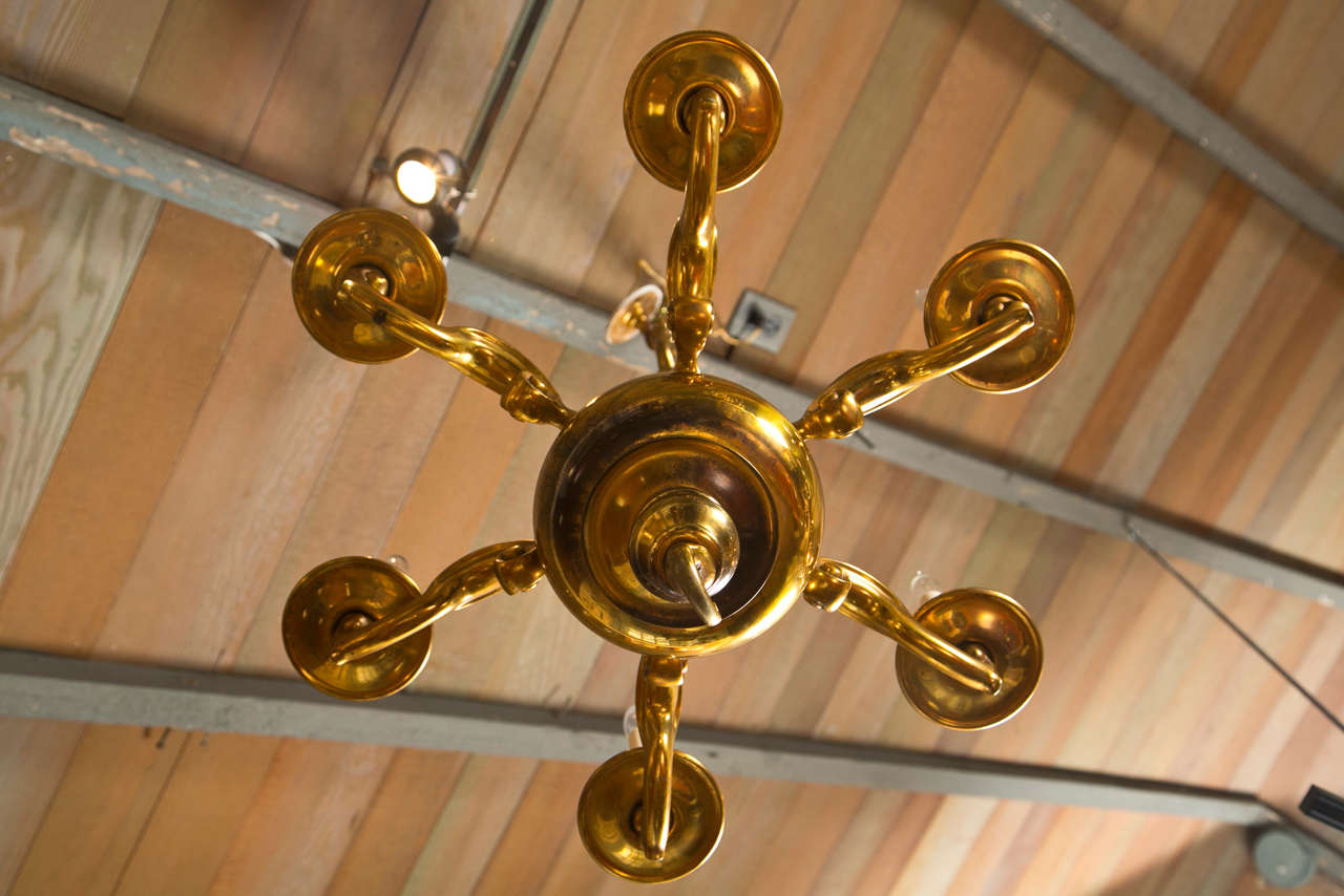 This solid English brass chandelier with six electrified arms has a visual weight to it that is augmented by its actual weight. Cast in solid brass, it offers the classic design elements associated with chandeliers, such as an urn shape in the post