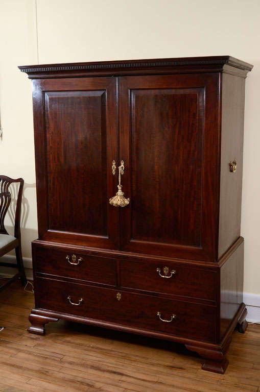 Beautifully proportioned English, mahogany linen press, circa 1790 in two parts. Dental molding over the two paneled doors, two smaller and one long drawer on bracket feet. Brass handles. Lined interiors.