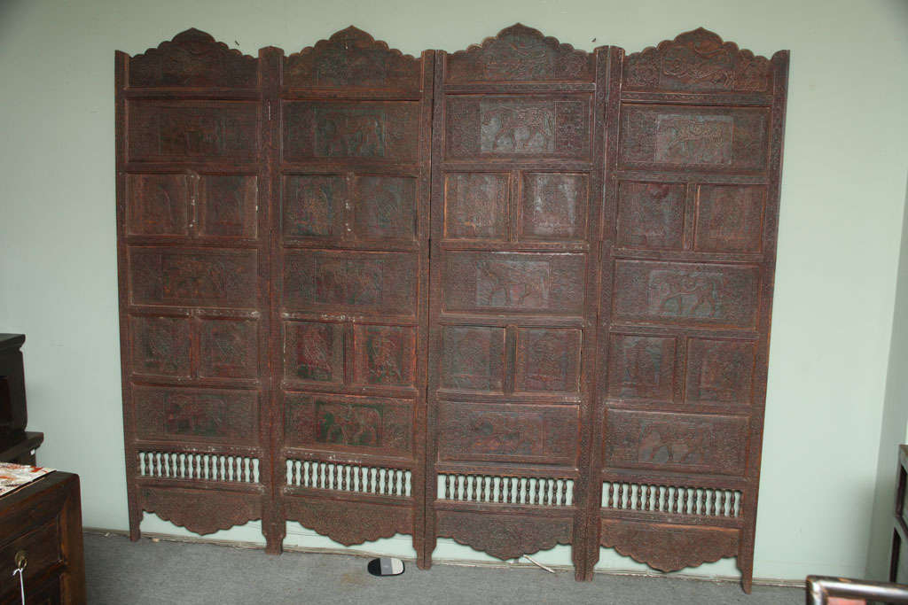 Large paneled teak wood screen with carved animals from the early 20th century. This Indian early 20th century large screen features hand-carved intricate animal patterns on its teak panels. The four panels display an exquisite dentate triangular
