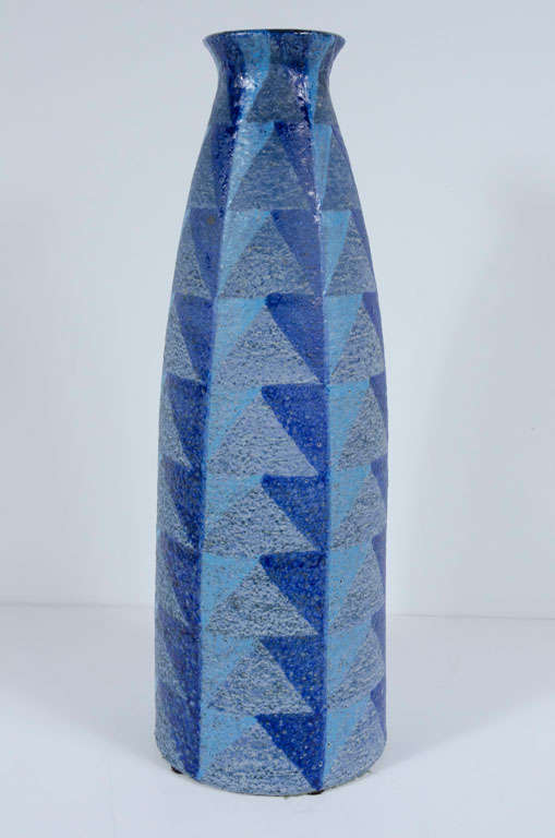 A tall ceramic vase with a mottled glaze geometric design in blues and greys to the exterior and a sleek high gloss black glaze interior. By Bitossi. Italy, circa 1950.