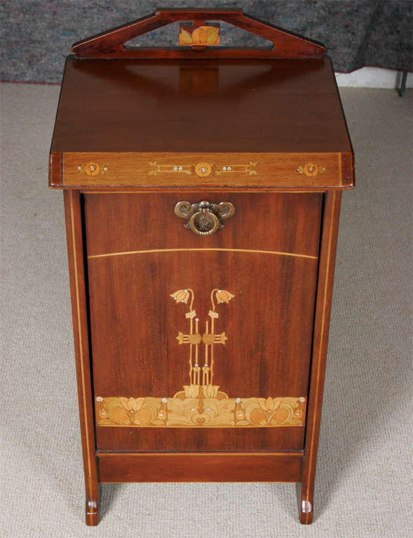 A coal Cupboard Purdonium in the Art Nouveau style.<br />
The Mahogany veneer inlaid with boxwood, harewood, tulipwood and mother-of-pearl, depicting stylized flowers.<br />
Brass handle.<br />
Tin interior.<br />
English<br />
Circa 1900<br
