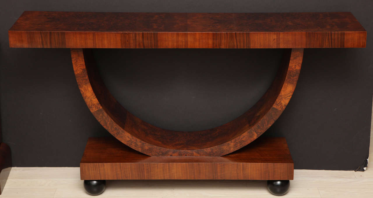 Walnut consoles on curved supports resting on rectangular plinth base.