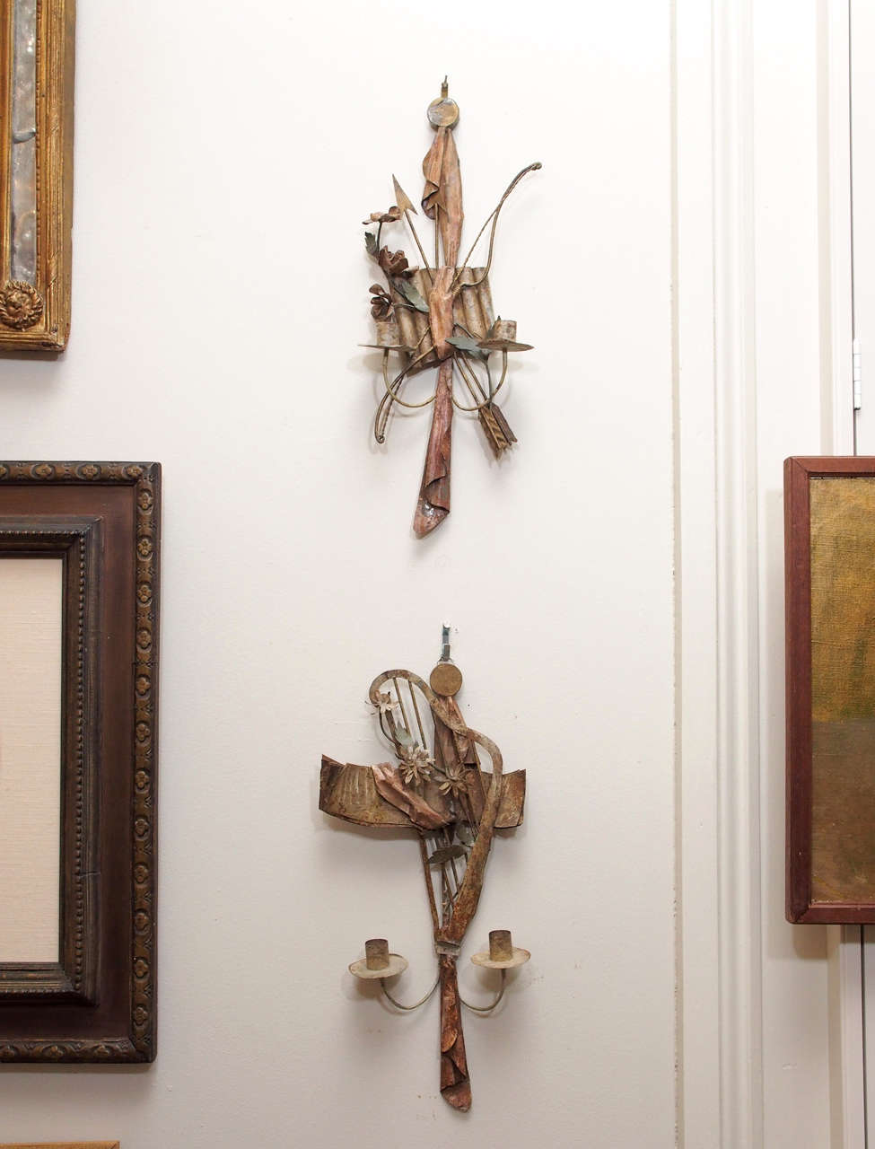 A pair of delightful, finely wrought tole wall lights, one a trophy of music, the other of the hunt, the wall light representing music having a harp and sheet music mounted over a drape and with flowers, and the other with a bow and arrow mounted