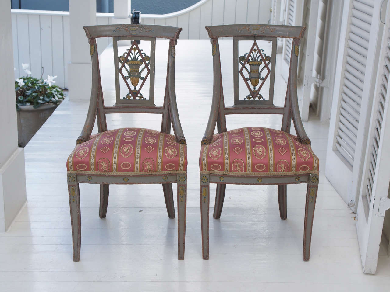 A pair of finely carved and painted Empire seats, the flared, en gondole backs with a lozenge framing an urn, the saber legs molded and topped with rosettes. Very sturdy and newly upholstered in a Brunschwig & Fils Empire style fabric.