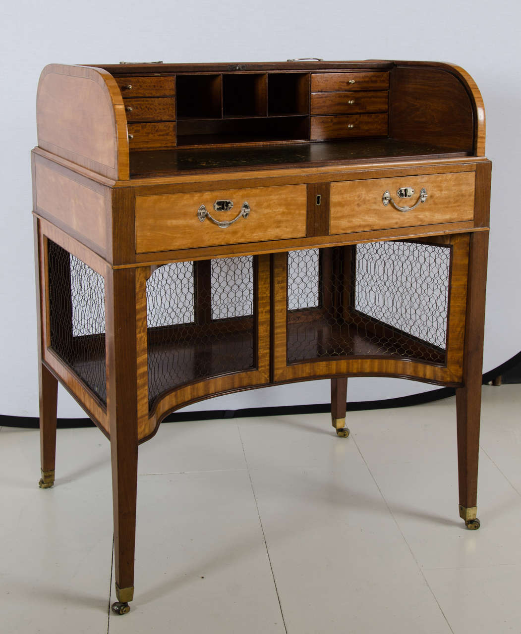 Sheraton mahogany and satinwood roll top ladies writing desk with an enclosed shelf below, accessed by concave doors. Silver hardware.