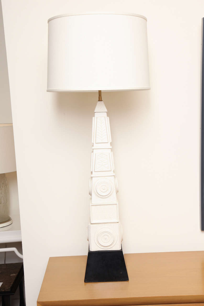 Tall ceramic lamp with raised designs on a wooden base with white linen shade. Lamp is rewired and height is adjustable, circa 1960.