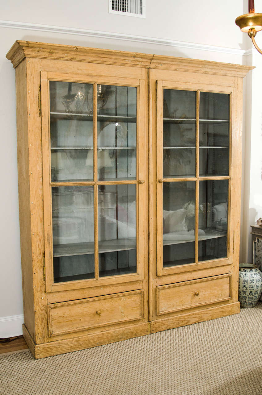 A wonderful tall wood cabinet (in two parts) with painted interior, five interior shelves, two lower storage drawers and beautiful doors with original glass.