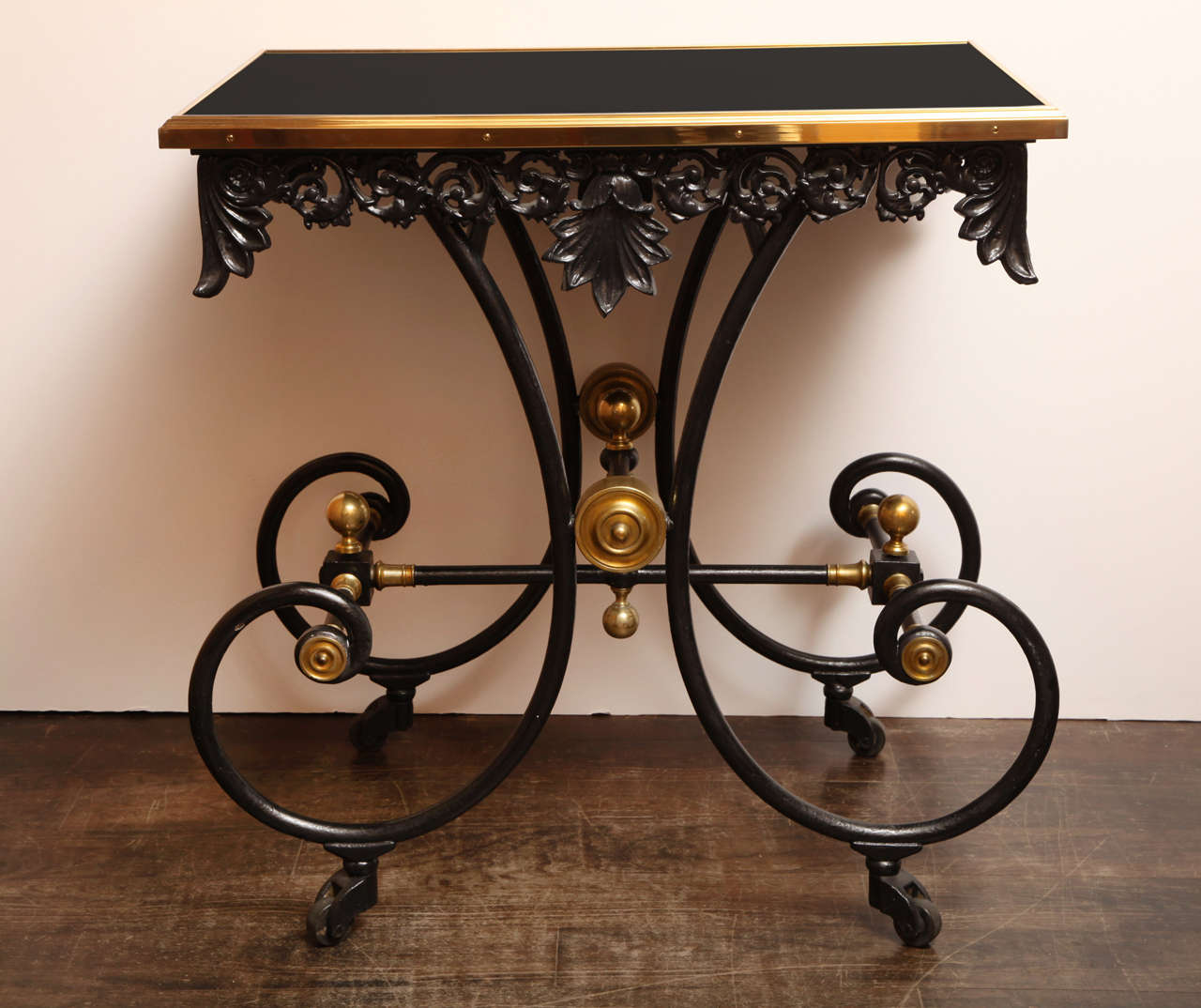 Esta encantadora y estrafalaria mesa de hierro fundido pintado de negro del siglo XIX está montada sobre ruedas y equipada con un moderno tablero de cristal opalino negro a medida enmarcado en bronce por Guerin.