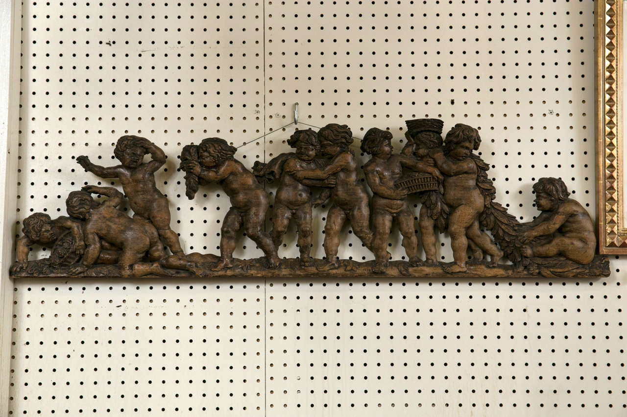 Frolicking nude cherubs holding garlands and baskets. Well detailed hand carving.