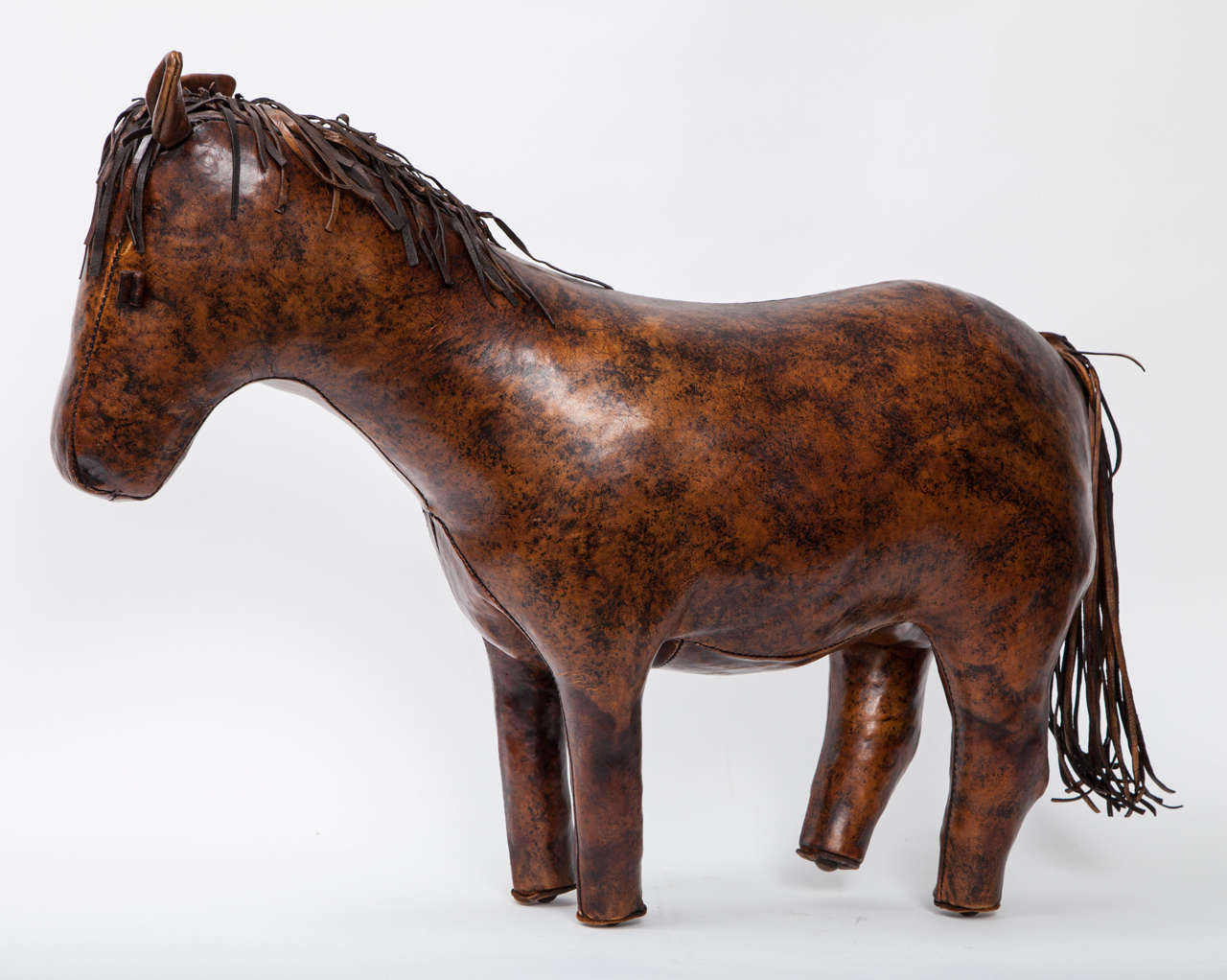 An ottoman / foot rest in the form of a horse made by Omersa for Abercrombie & Fitch.  England, circa 1960. Features burnished, mottled brown leather with hand stitching.