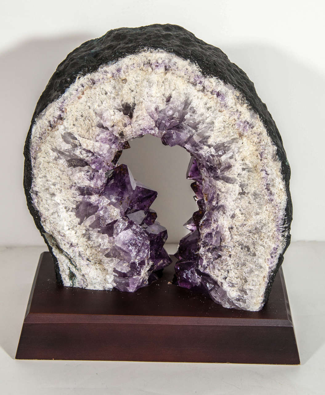 Outstanding geode speciman and sculpture with unique horse shoe form. The geode is comprised of quartz crystal and amethyst chunks in gradient tones of whites to deep purple.  It features a hand cut and polished front with rough edges, and has a