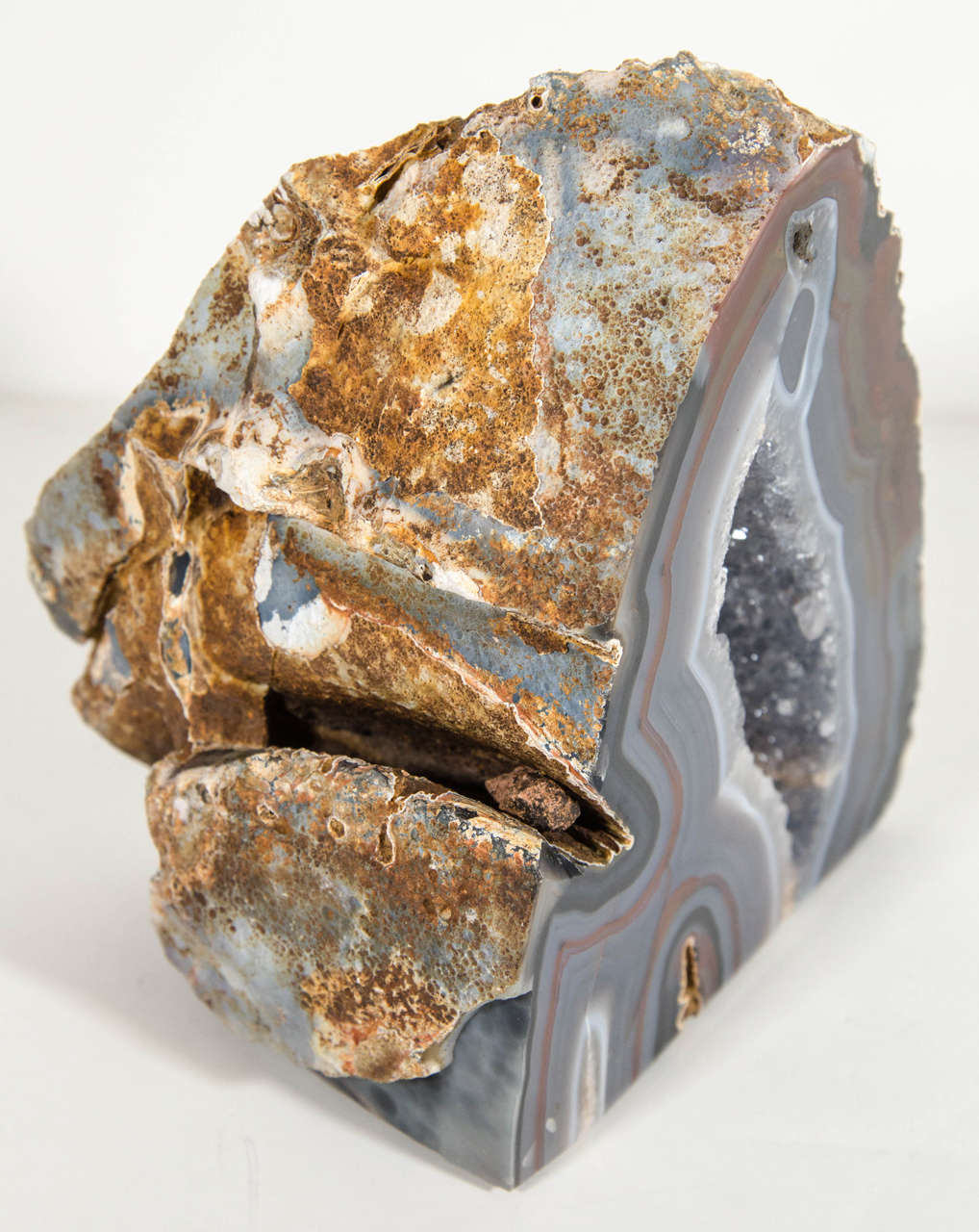 Gorgeous agate stone specimen sculpture with polished front and rough edges. The stone piece has variant hues of grey, browns and black tones with a grey fine crystalline center. Makes a great decorative object or as a bookend.