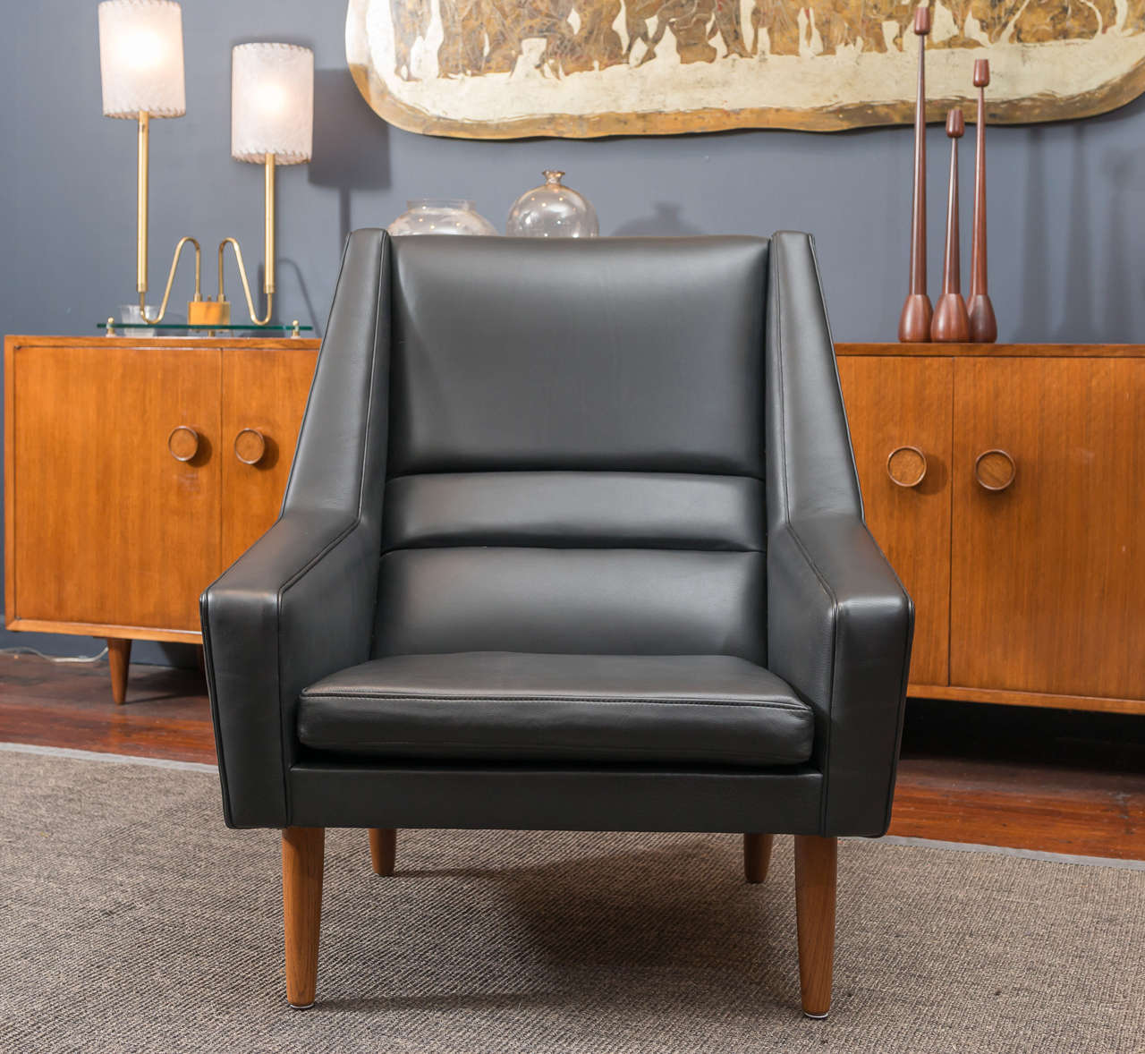 Supreme man's chair newly upholstered in black leather with refinished teak legs.