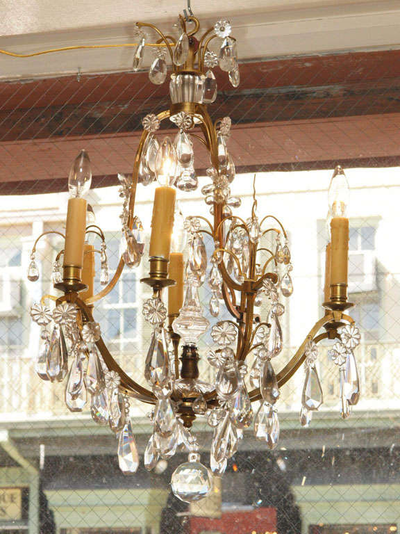 Crystal and bronze chandelier by Maison Jansen, France, circa 1920. The iron frame of this cage form chandelier is finished in antique gold and decorated with crystal pendalogues, U-drops, grape crystals and fleurettes. The bottom of this chandelier