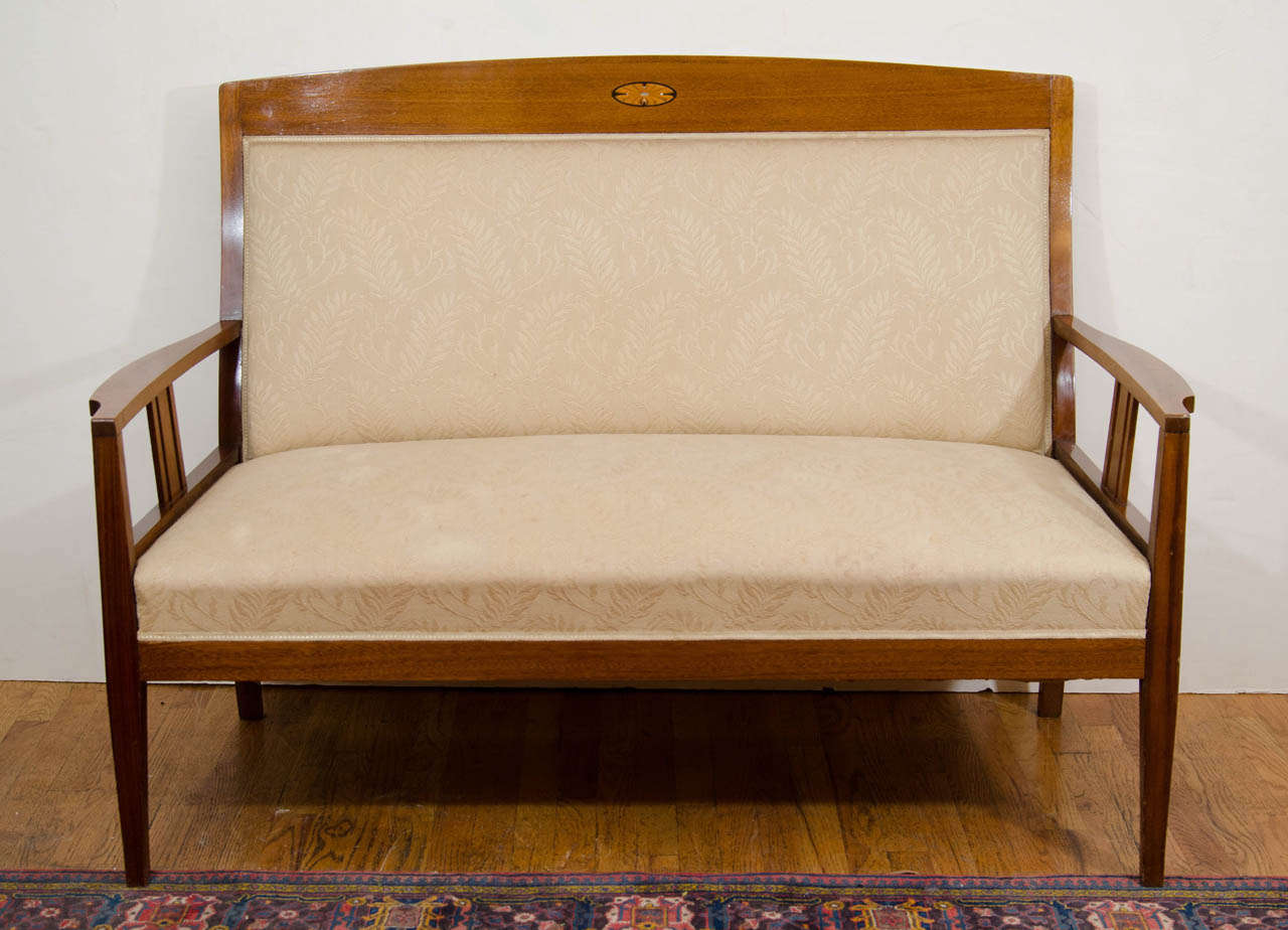 A solid mahogany loveseat with ebony, birch and mother-of-pearl inlays, this piece is part of a suit which included the aforementioned Armchairs. Created at the beginning of the twentieth century, the design is the Swedish cousin of Charles Rennie