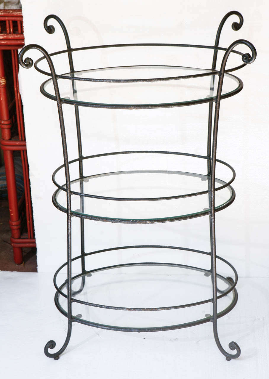 Beautifully crafted 1940's wrought iron table. Curved legs at top and bottom. Three oval shelves with gallery rails. Shelf surfaces measure 22
