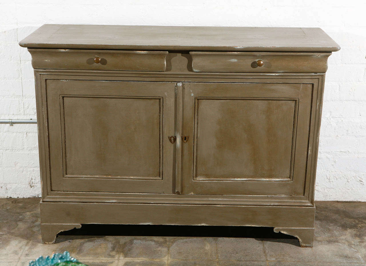 A good stylish Louis Phillipe server with a distressed bluish grey/taupe finish. The cabinet has two doors and one shelf. The server has two good sized drawers with a built in partition in one. This piece will look good in all types of settings and