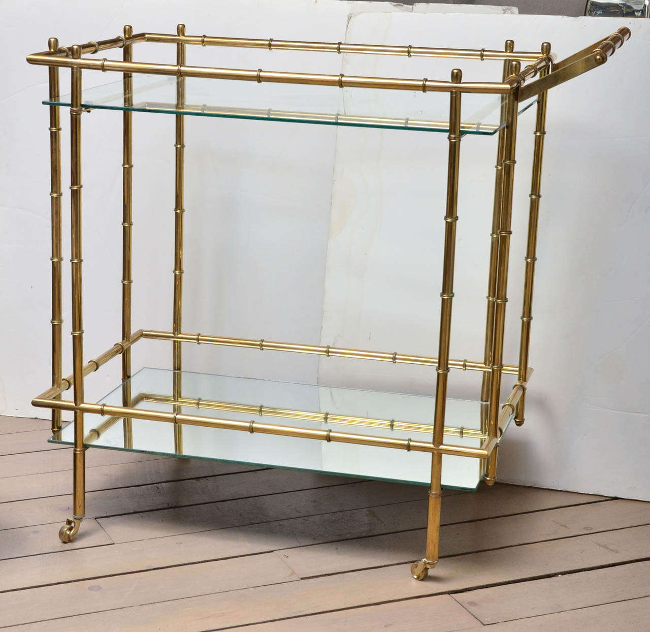 This faux bamboo brass bar cart with mirrored bottom glass and clear top glass with wheels is a great addition to any home!