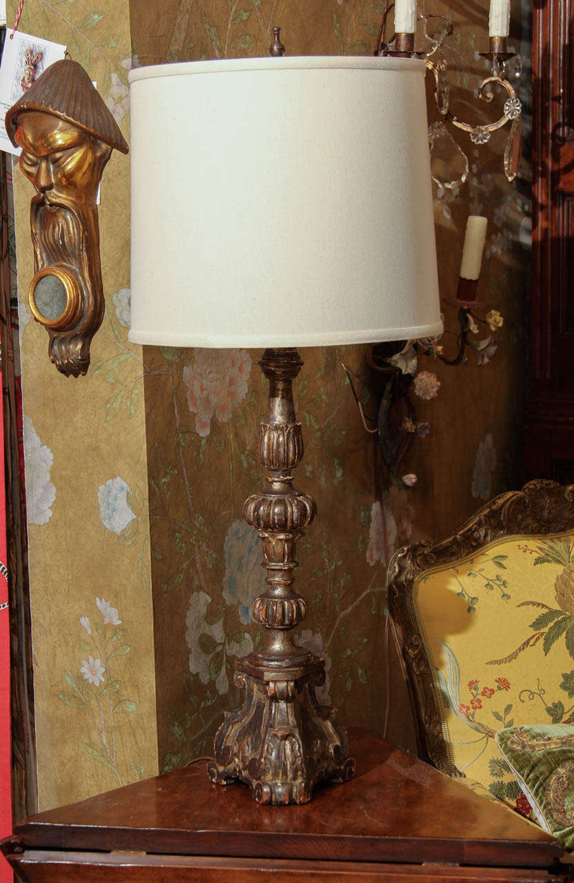 An early 20th century Italian carved and silver gilt candlestick converted into a table lamp.