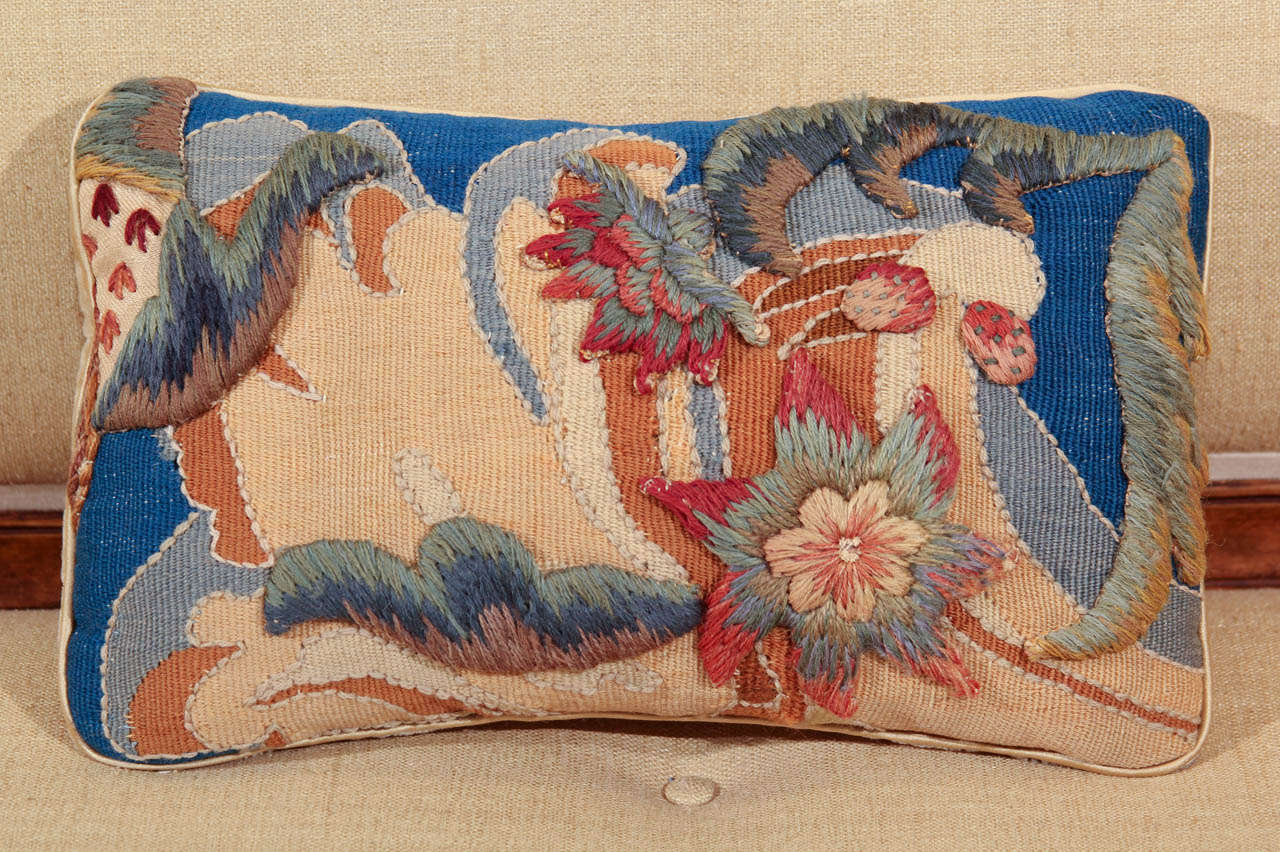 A pillow made from a 19th century aubusson fragment  highlighted with over stiching and appliqued with early 20th century wool crewel work.