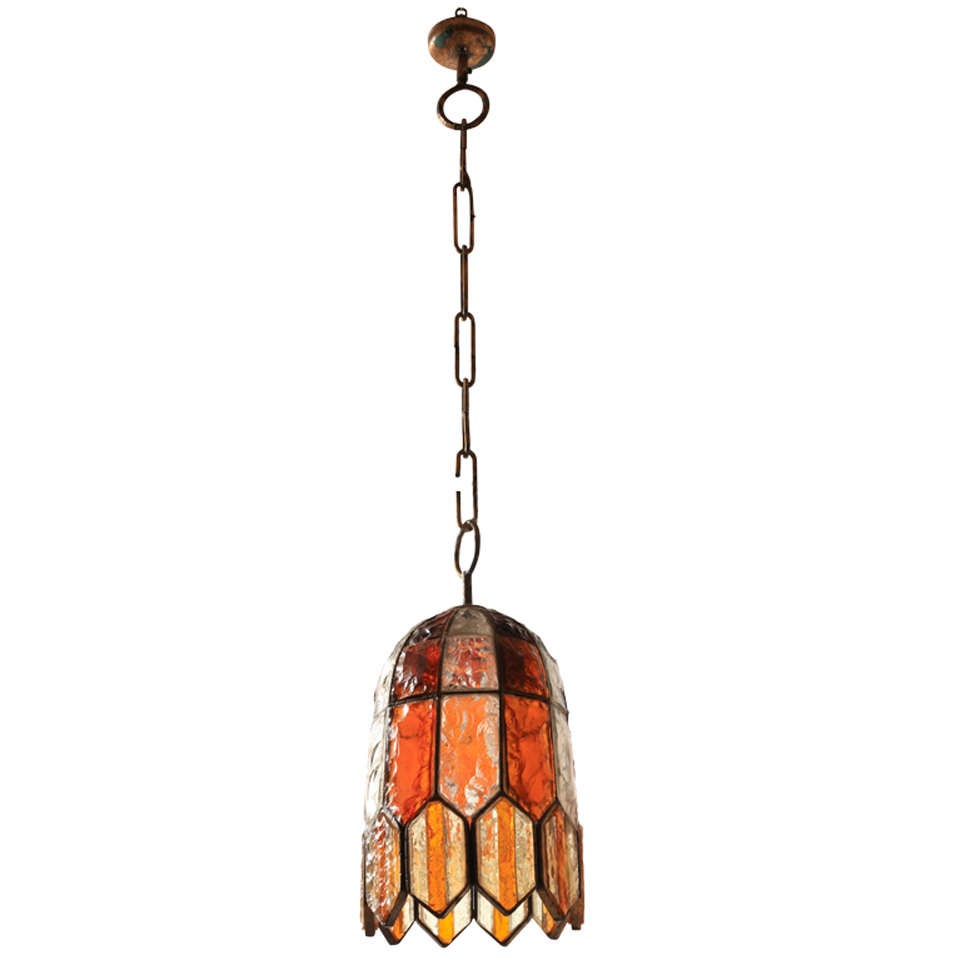 This contemporary brutalist wrought gilded iron chandelier designed with amber and clear glass pieces gives a special atmospherisch light typical for the Italian designer of Poliarte's work in the 1970s. 
The designer created several models of