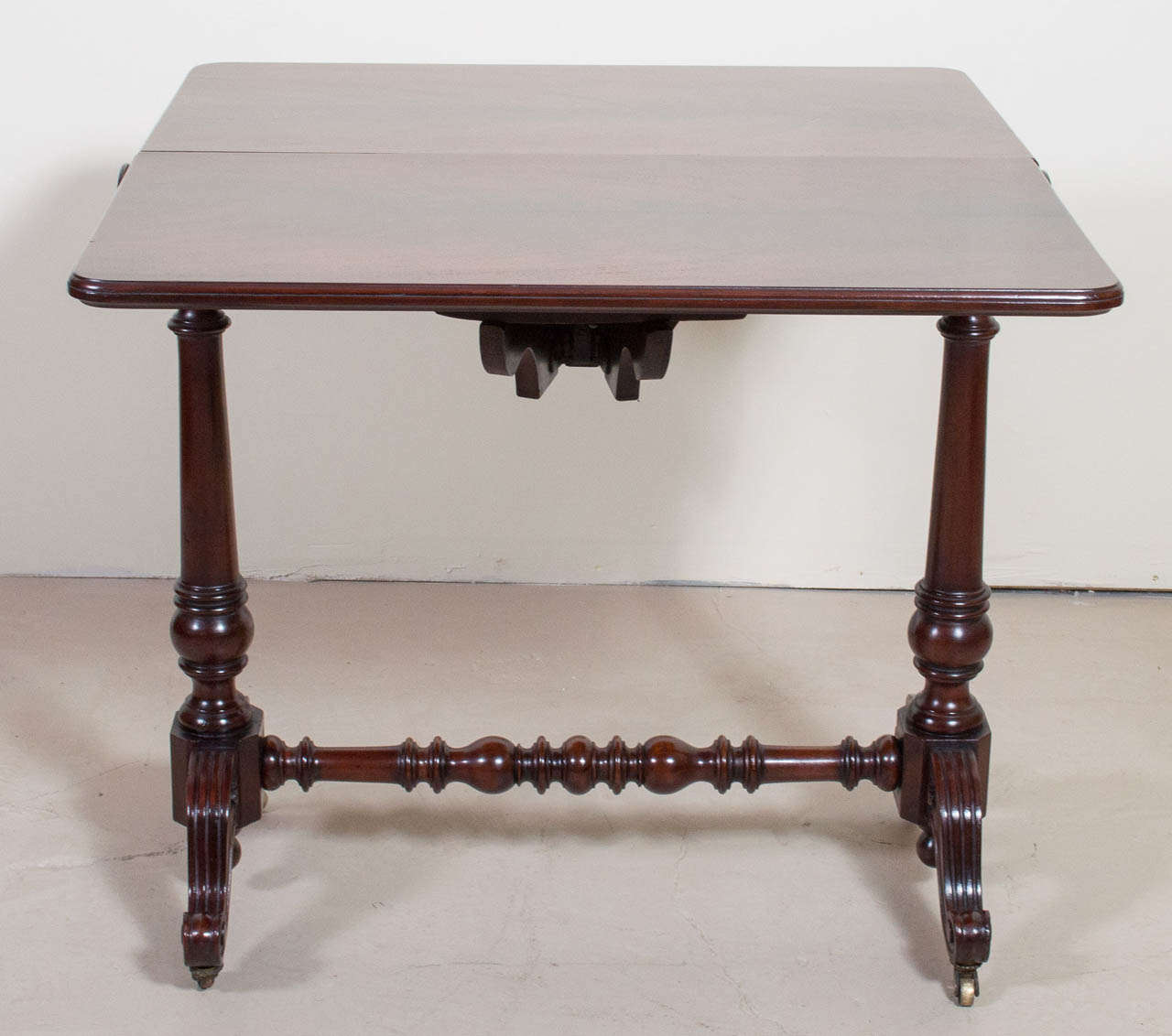 A unique and unusual Victorian flame mahogany leaf lap table. The cylinder hinged top allows one or both leaves to completely drop. The table is supported by two turned legs joined by a turned stretcher on castors. This table retains its beautiful,
