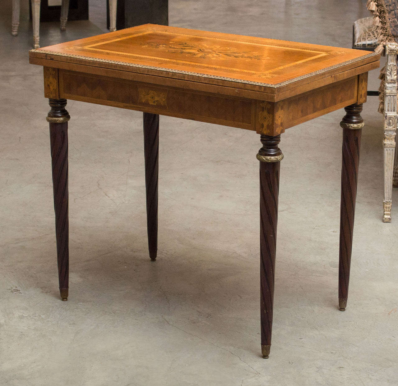 Late 19th Century French fruitwood card table with elaborate mahogany and satinwood inlay depictive vines and musical instruments with bronze detailing and bookmark apron on carved turned legs. Circa 1890