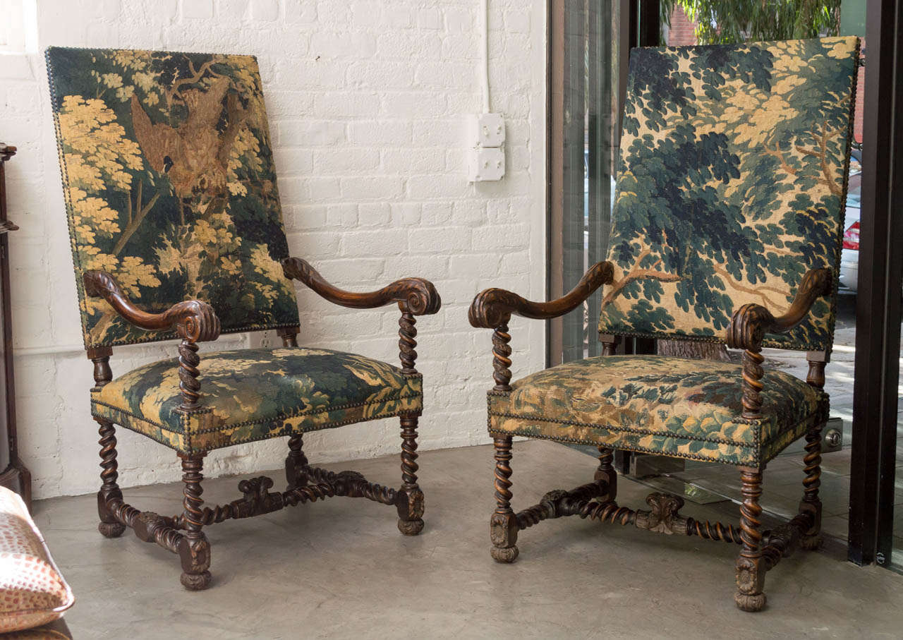 Pair of period Louis XIII Eighteenth Century hand carved walnut fauteuils all hand carved with acanthus leaf hand rests and twisted supports culminating in sunflower blocks, on foliate bun feet. Each Upholstered in 17th century Flemish tapestry with