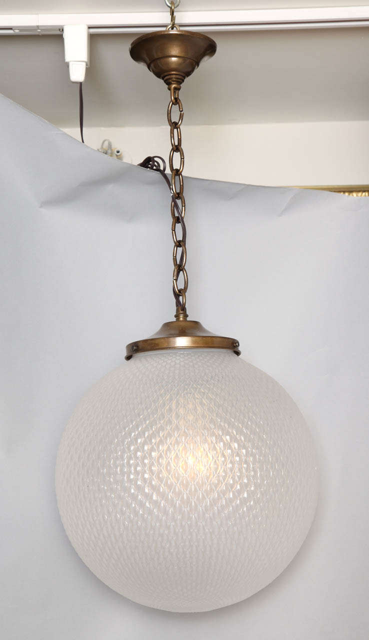 Un luminaire à globe sphérique en verre opalescent avec une surface texturée et des raccords en métal nickelé argenté.