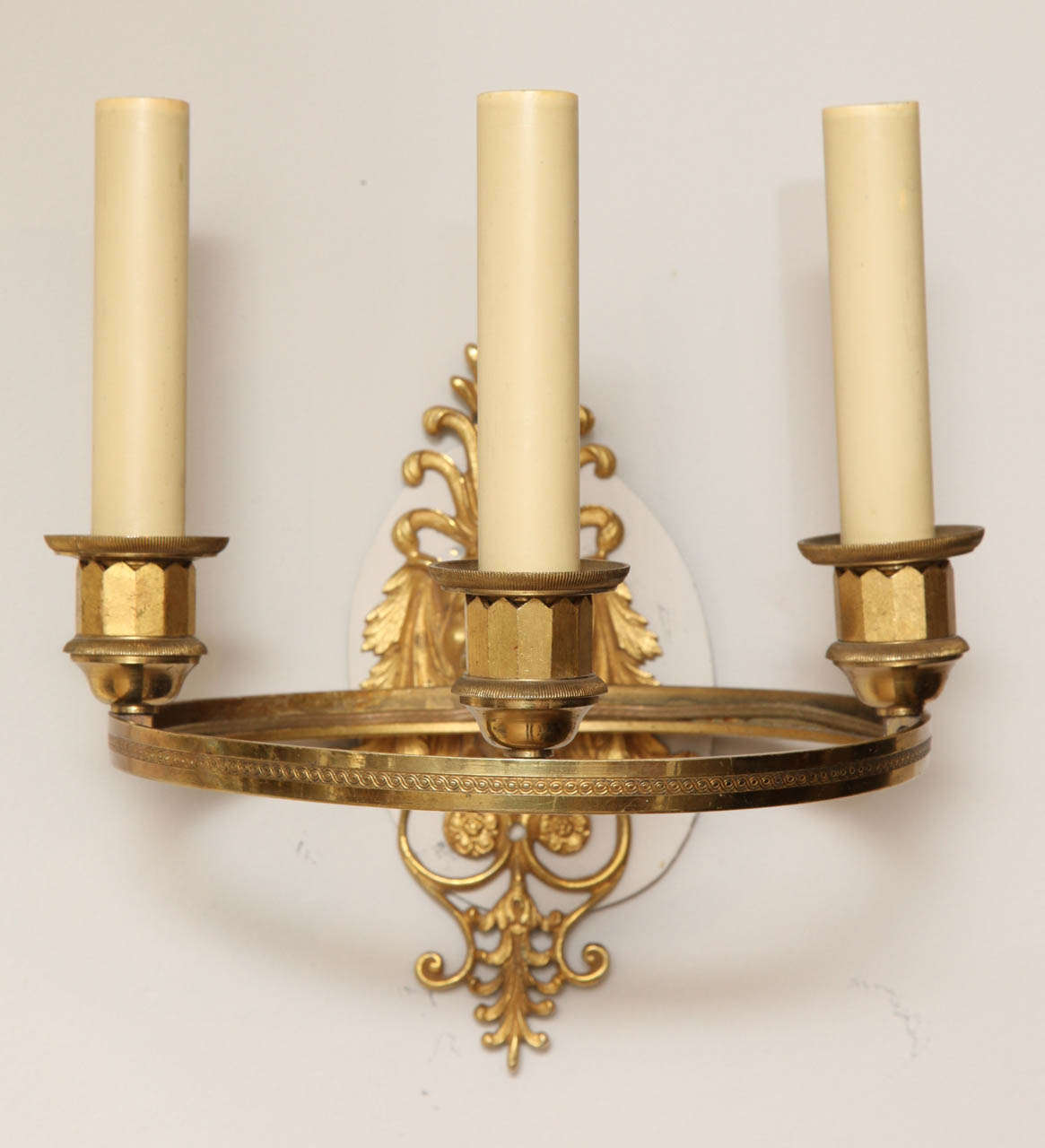 A pair of Charles X period French Empire style ring-form sconces with three lights having a lion's mask backplate.