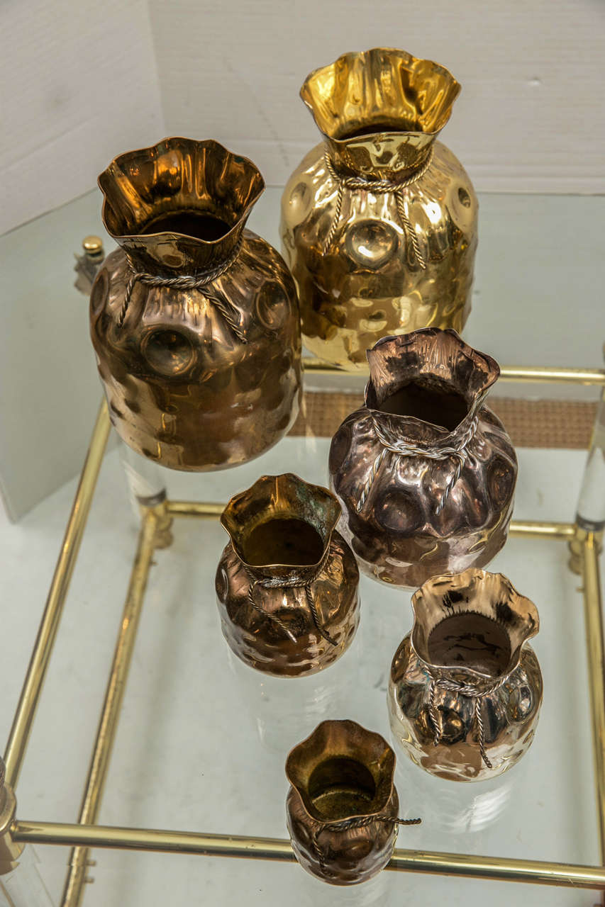 A lovely grouping of metal containers in the form of sacks with rope ties. Four of brass, two of silver plate.