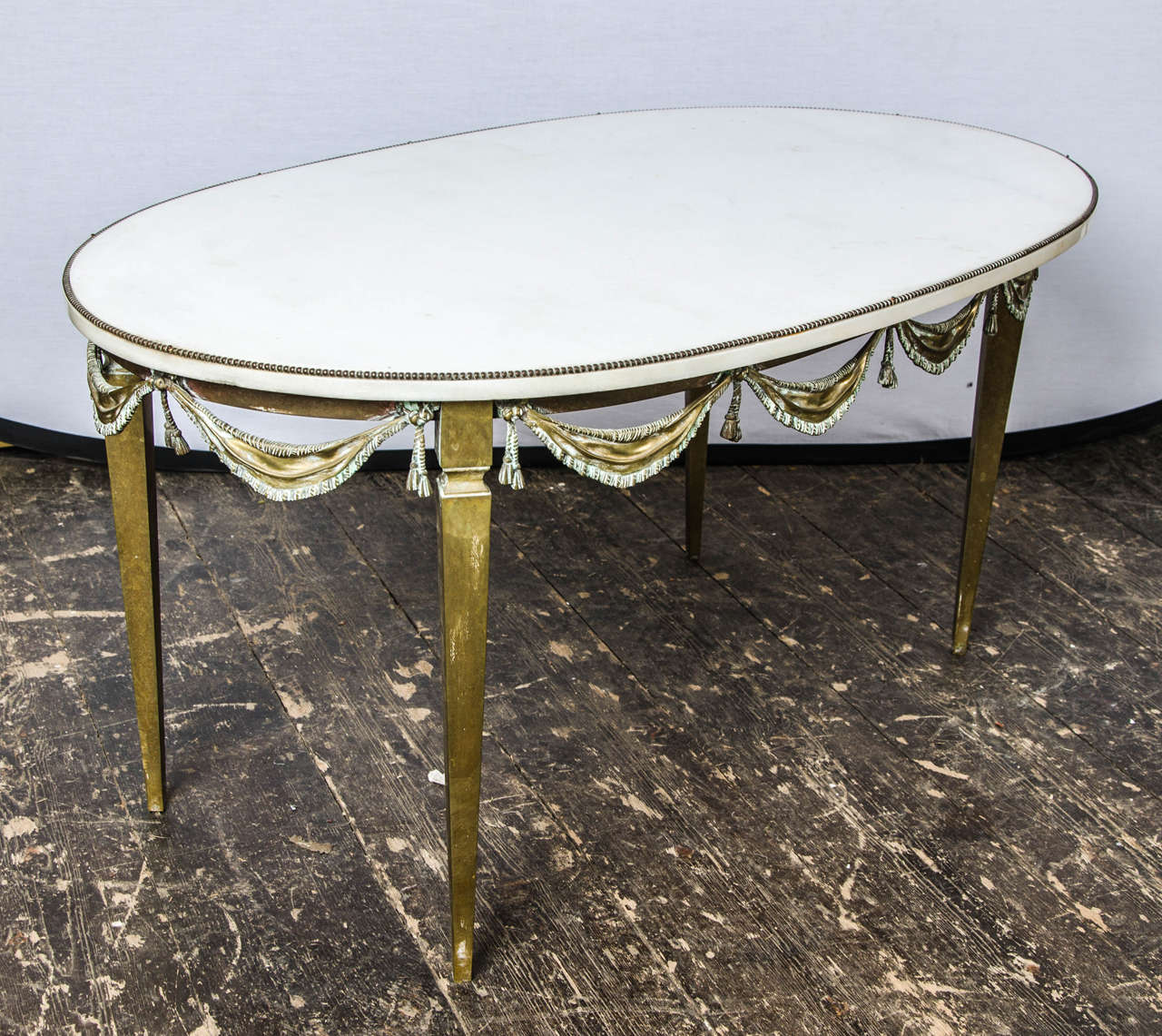 Art Deco French coffee table in original patina, and brass ribbons going around with a white marble top