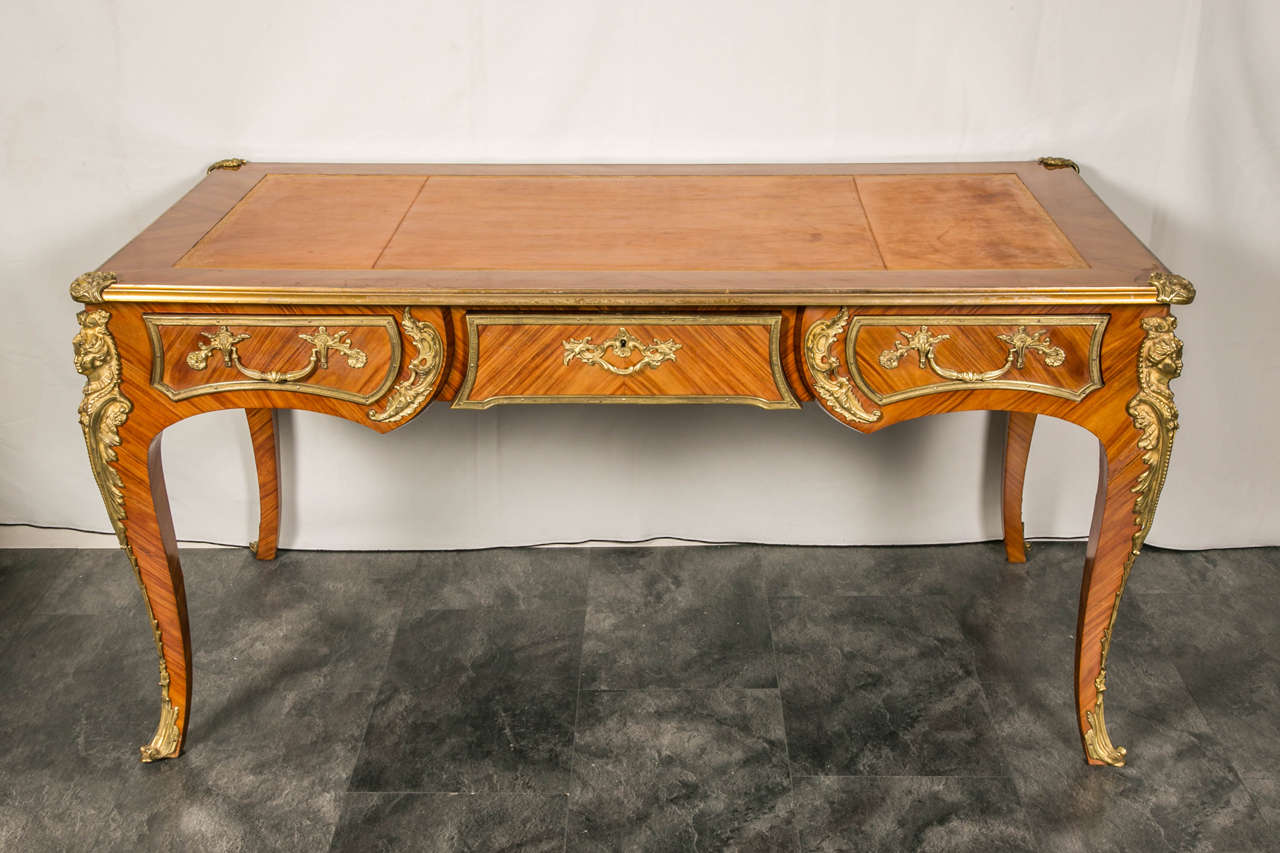 Very fine work in amaranth and kingwood veneered Louis XV style bureau plat.
It has a shaped top with a tooled light brown leather writing surface with gilt tooling around the border above a frieze with three drawers to the front and simulated