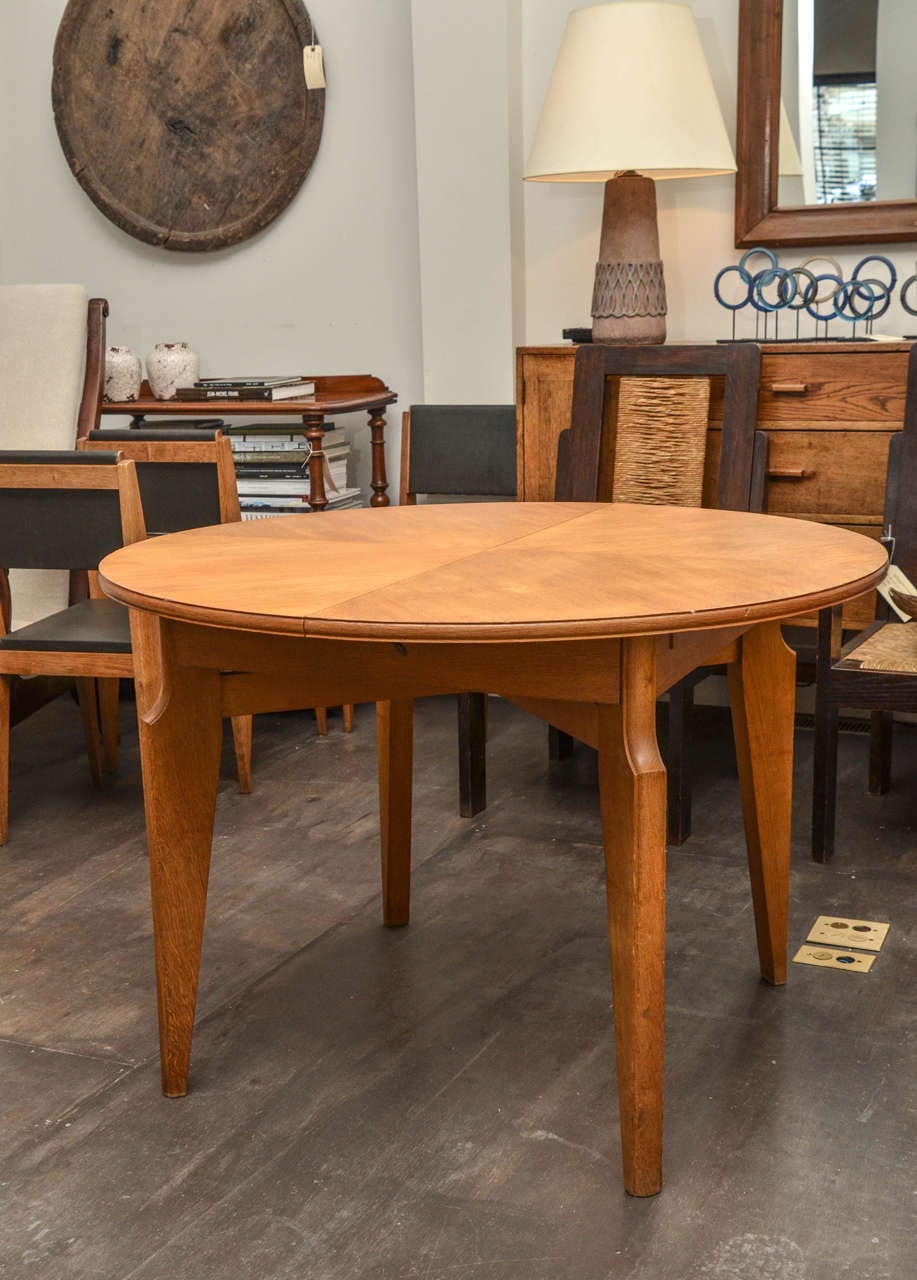 Beautiful round mid-century oak dining table, France. 

Table consists of a handsome round top set on angular, tapered legs. 

The table has been lightly refinished and treated with a clear coat of wax. 