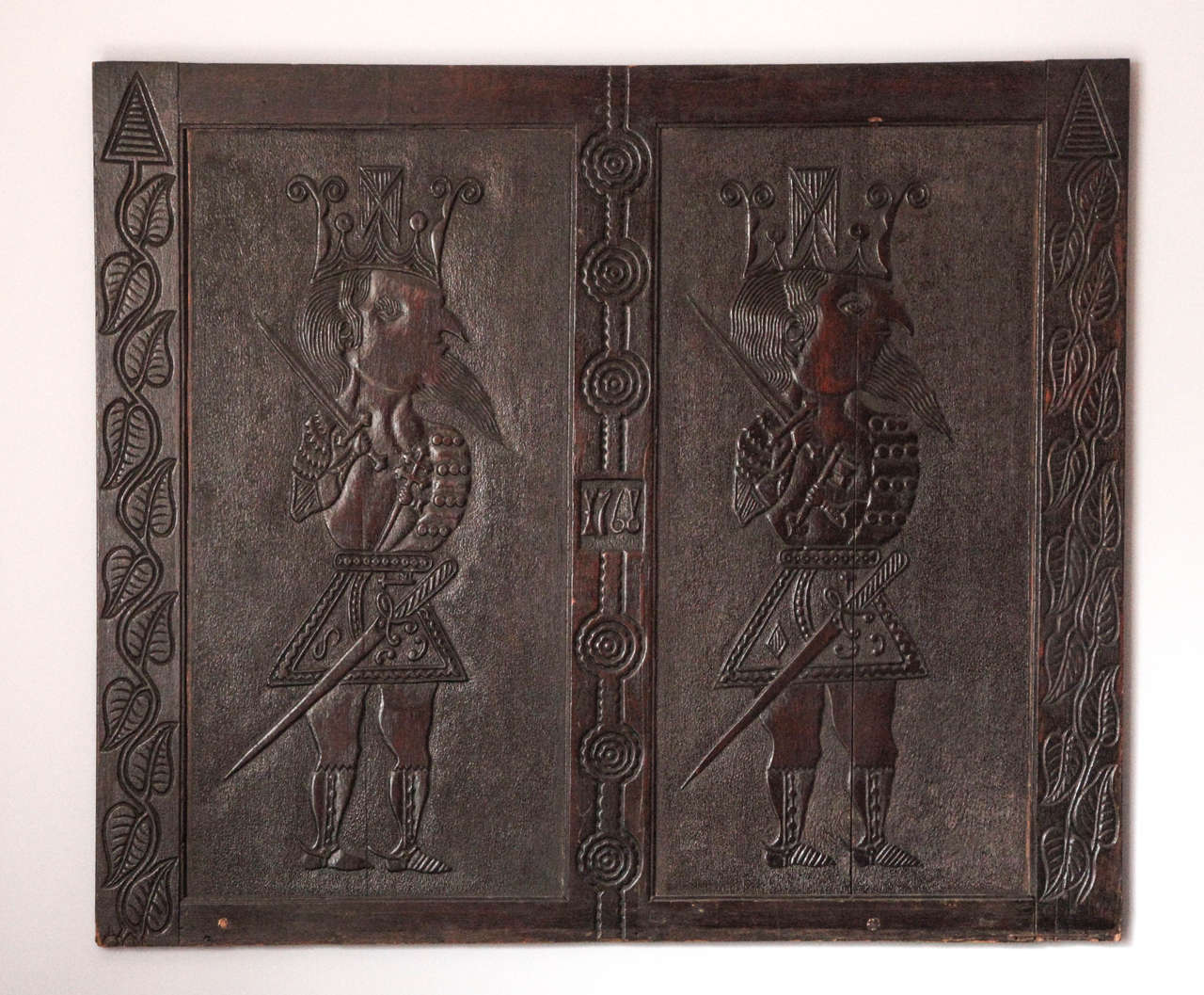 Unique carved Folk Art panel, dated 1768, depicting a double portrait of mythological kings, whimsically portrayed in miniature stature with protruding beards and chests, from an 18th century manor house in Cambridgeshire, Dalham Hall and was