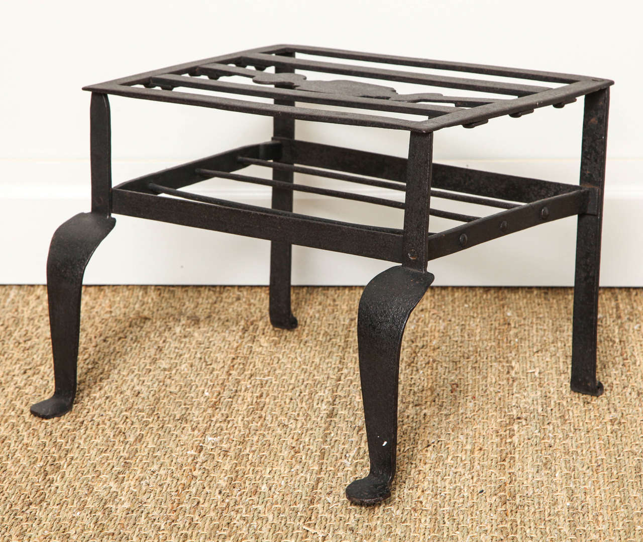Good late 18th century wrought iron footman or trivet, the slatted top with shaped centre spat, the front cabriole legs with penny feet, the whole with good patinated surface.