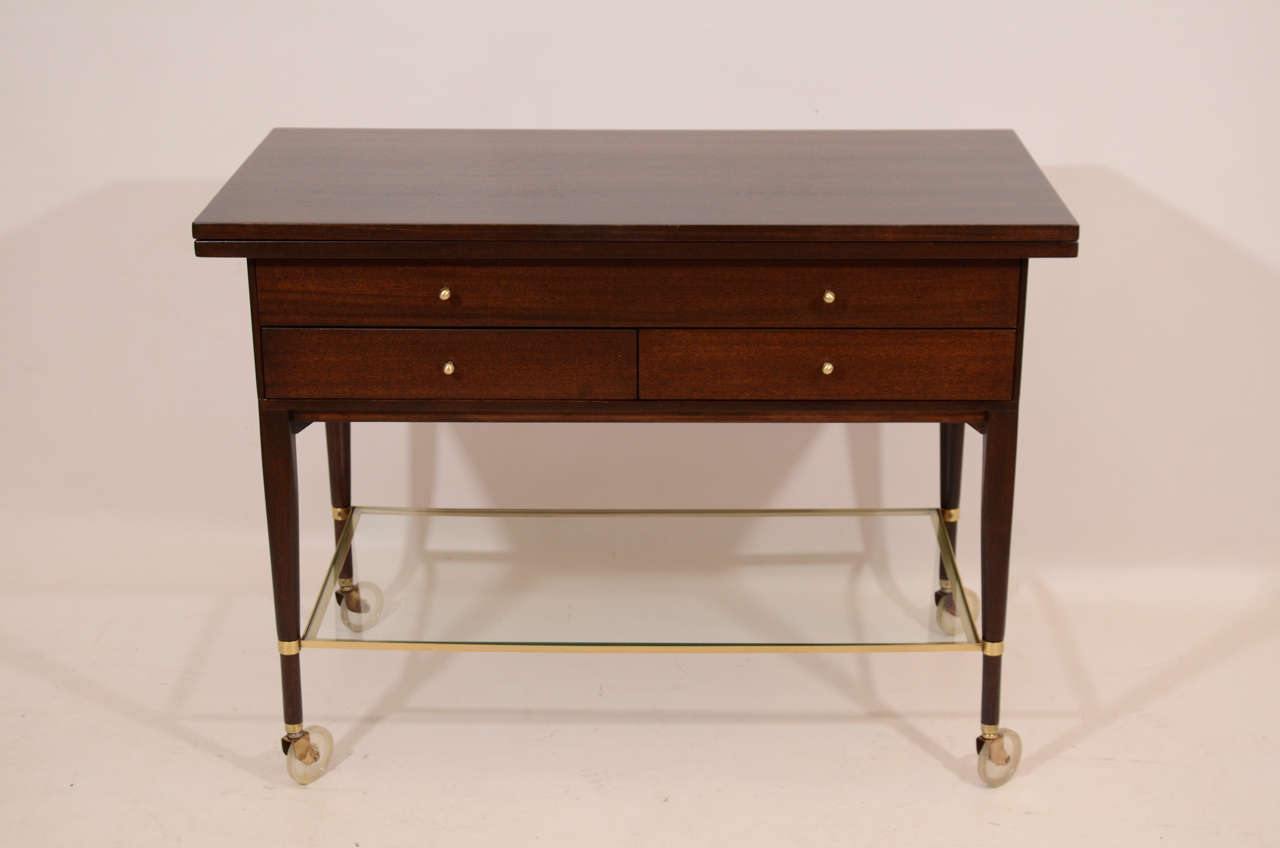 Elegant bar or serving cart and cabinet designed by Paul McCobb for his Calvin Group. The top opens to 80 inches for an expanded surface. Beautifully refinished mahogany in a dark stain; accented with polished brass. Please contact for location.