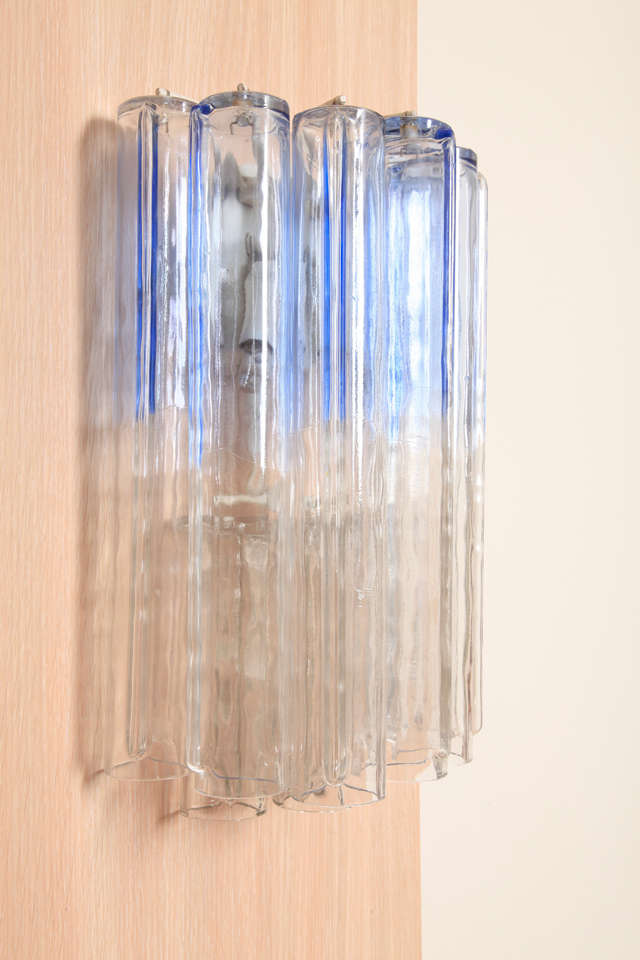 Pair of blue Calza wall lights (model 923.27) by Venini, glassworks in Murano? iTALY.
Each made of ten mould-blown glass elements (seven tall with a blue strip and three short in clear glass) a white-lacquered metal frame.
Impressed marks -Venini