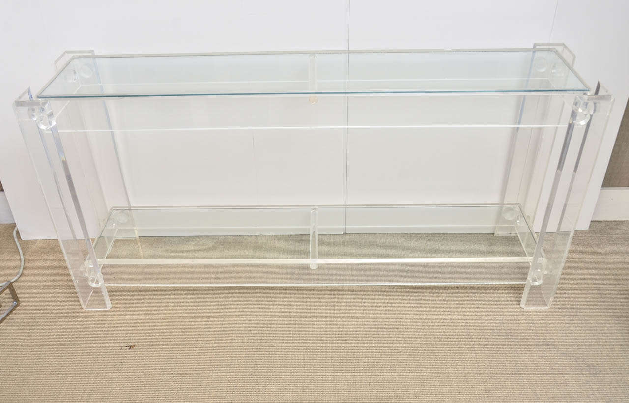 Vintage clear Lucite console with 2-glass shelves. The Lucite is clear and the cloudiness is camera artefact.