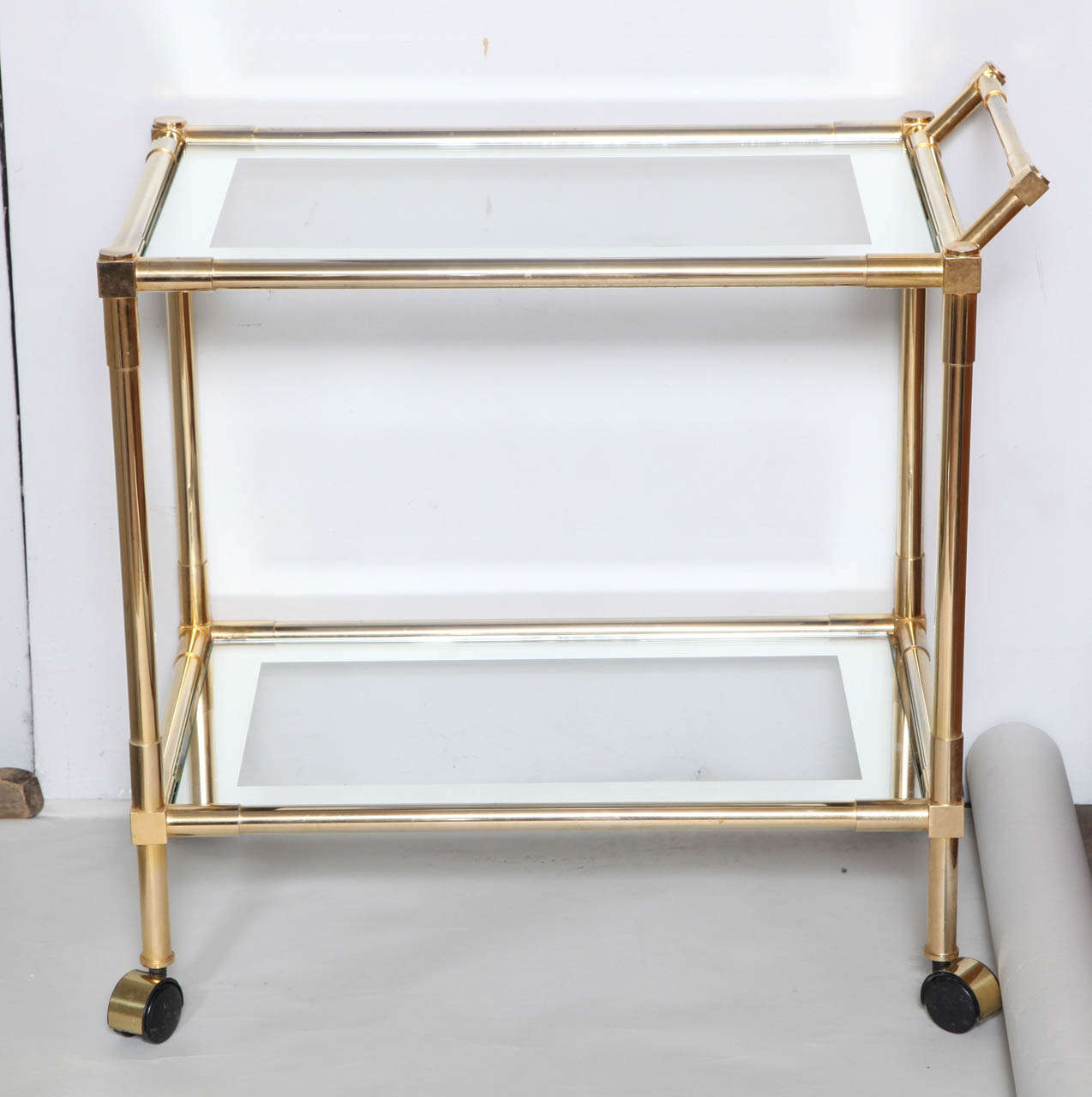 A elegant and sleek mid century designer bar cart with original mirrored framed glass. Finished in a brass vermeil and with squared off detailing.