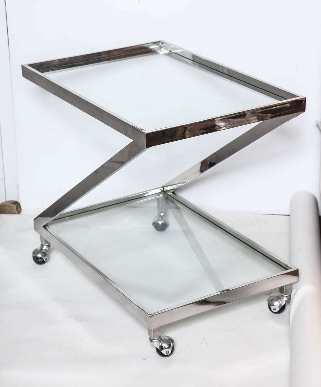 A sleek and practical designer glass and chromed metal stable Z form bar cart on four quality ball wheels