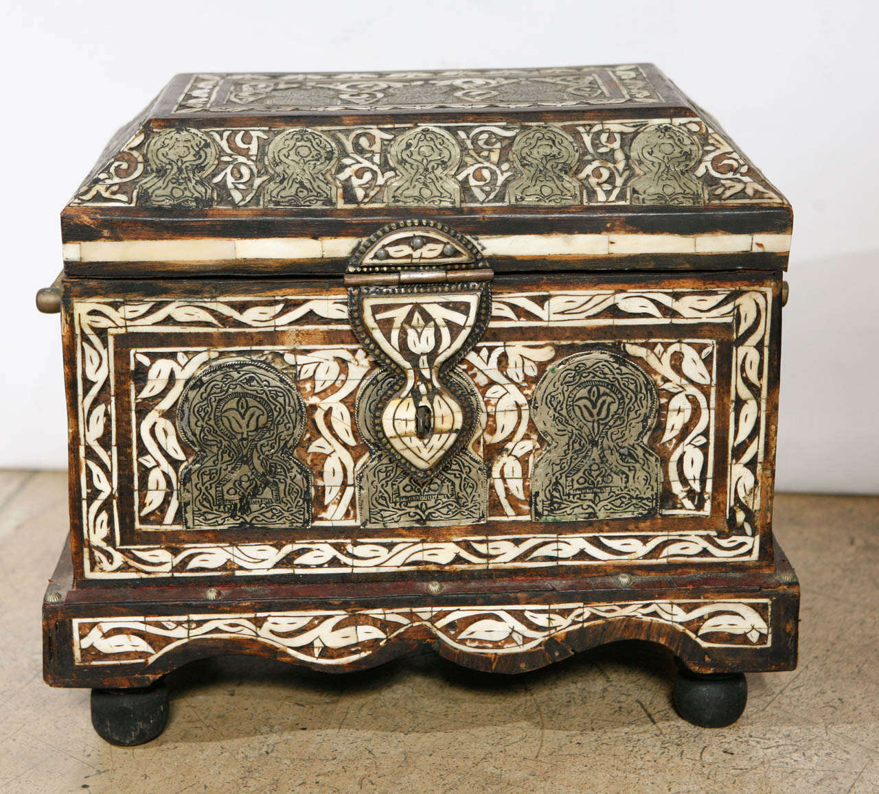 A early 20th Century bone inlaid Morroccan box. Also decorated with brass plaques on sides and top with an abstract Islamic design.  Ball Feet.