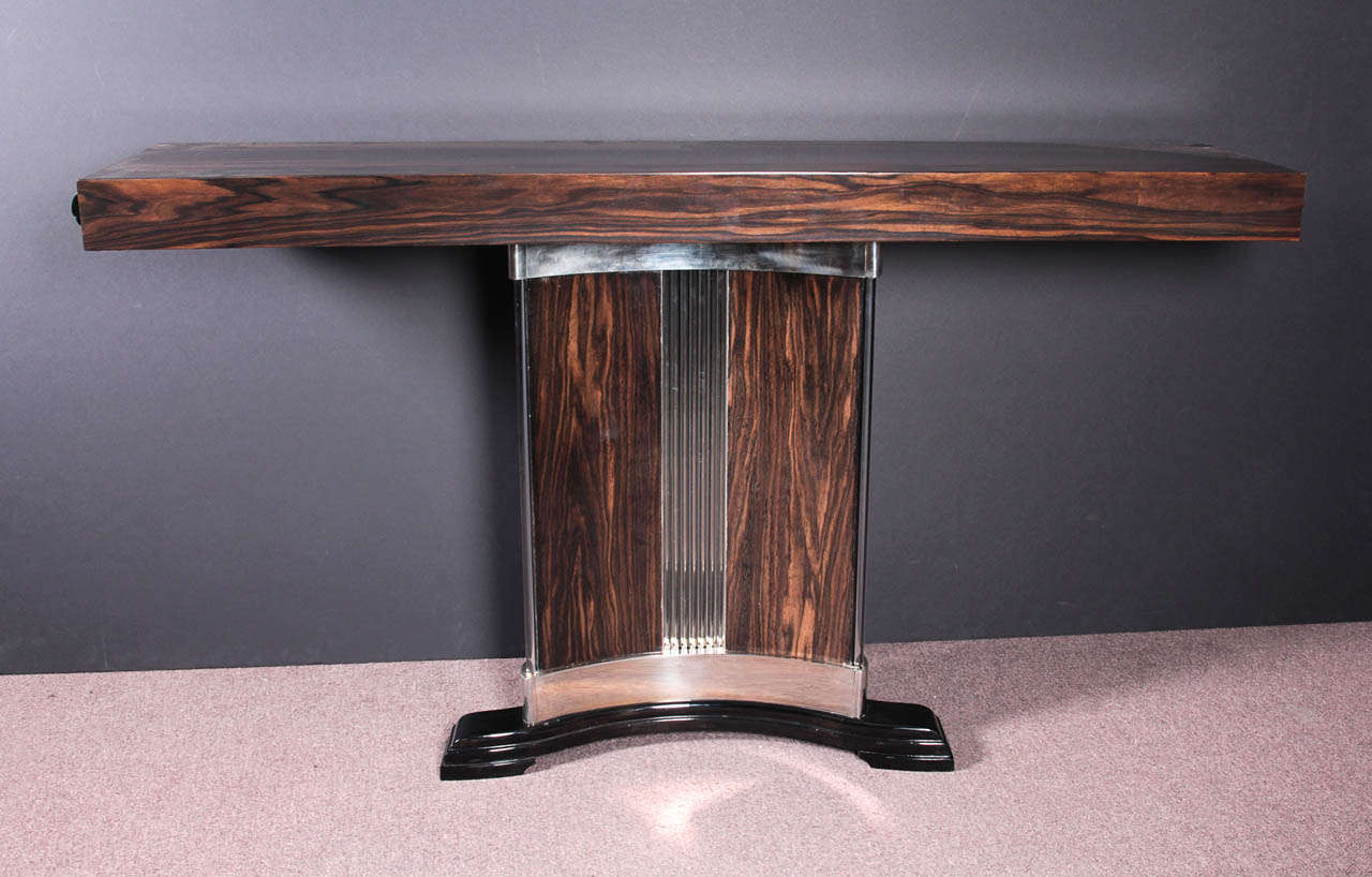 French Art Deco exotic macassar ebony, glass and nickeled bronze console.
Rectilinear in form with unusual concave front featuring a graphic arabesque of glass rods and polished nickeled bronze strips- attributed to Dominique @1930
High gloss