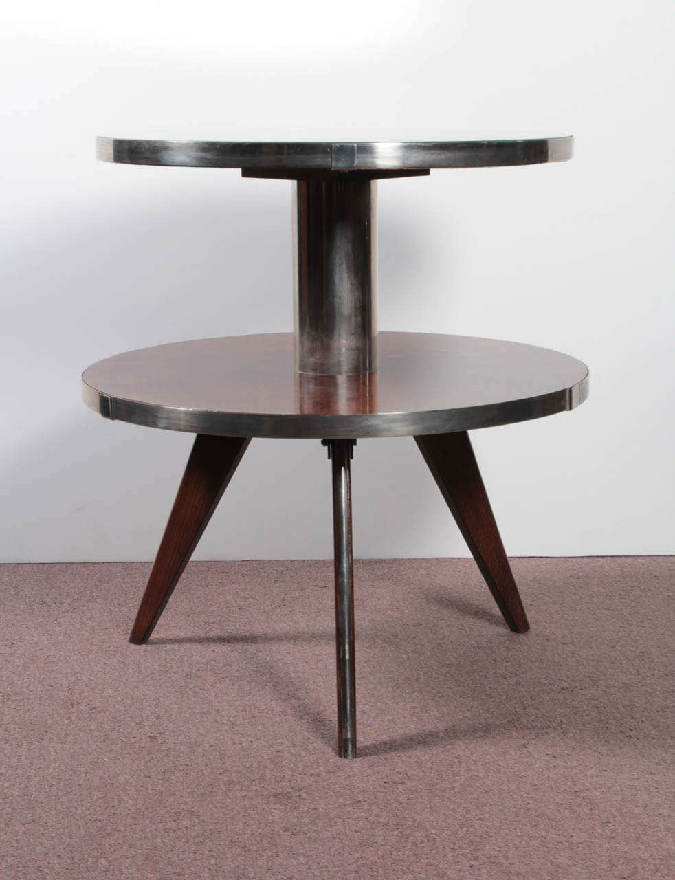 Sculptural French modernist 1940s two-tiered table in the style of Maurice Triboy. A circular mirrored top suspends effortlessly by a polished nickeled bronze column with circular bookmatched walnut stretcher shelf banded with nickeled bronze. Both