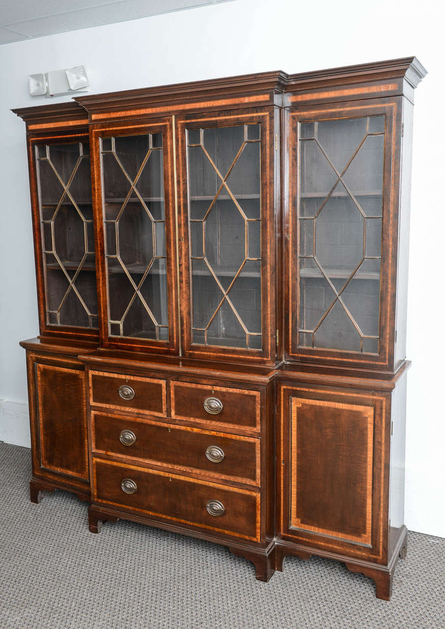 This is a very nice large mahogany breakfront bookcase made in England circa 1880.

The base has drawers to the center and either side there is a door which all have satin wood inlay to the edges.

The top has four doors again with satinwood