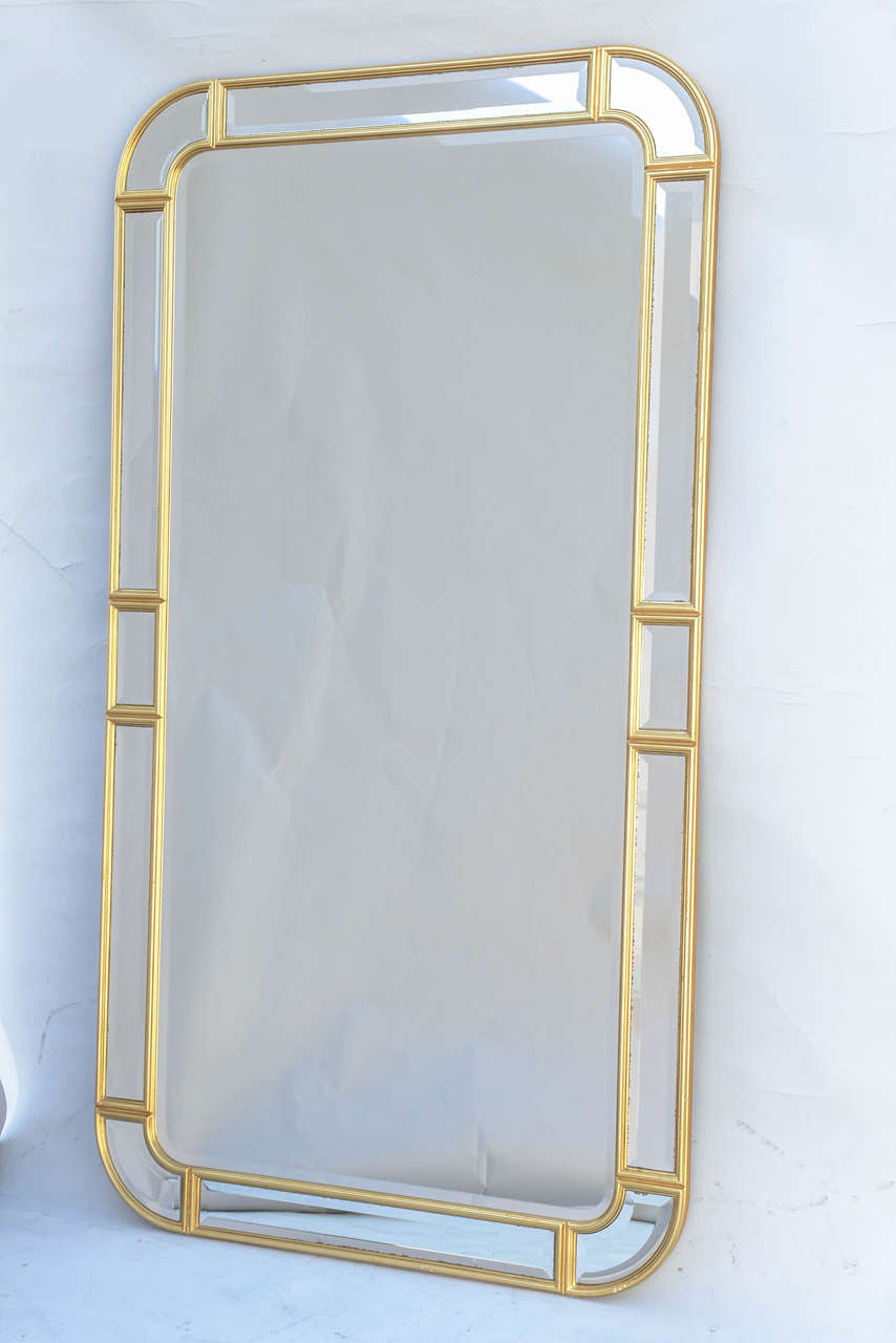 Mirror, having a rectangular form with rounded corners, its gilt molded frame inset with bevelled mirrored panels creating a relief frame, surrounding large bevelled mirrorplate.