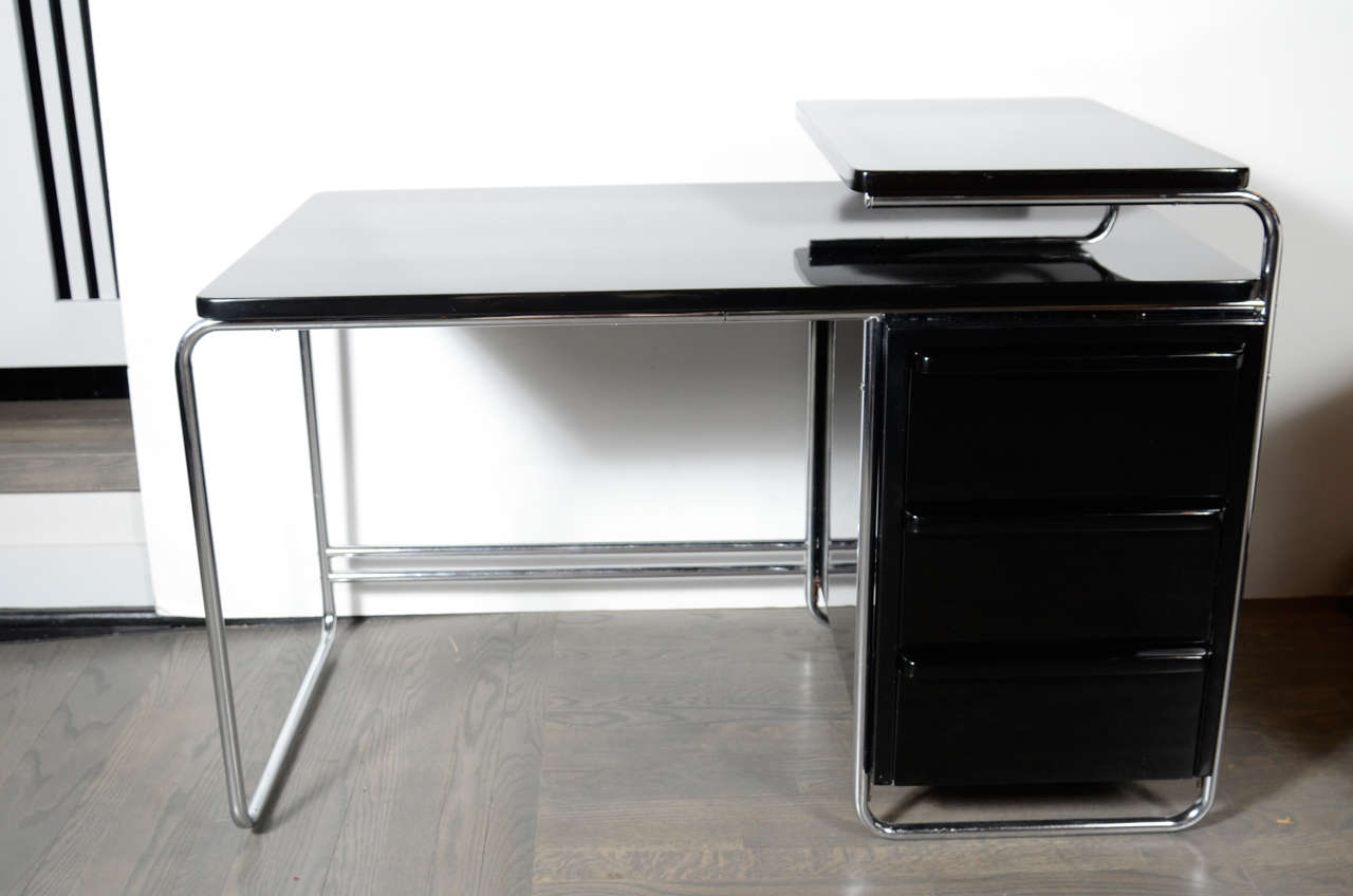 Streamlined Art Deco Machine Age desk by Wolfgang Hoffmann in Bauhaus style. Chrome tubular frame with black lacquer cabinetry. Includes three drawers for storage and a raised cantilever platform for additional work space. Restored to mint condition.