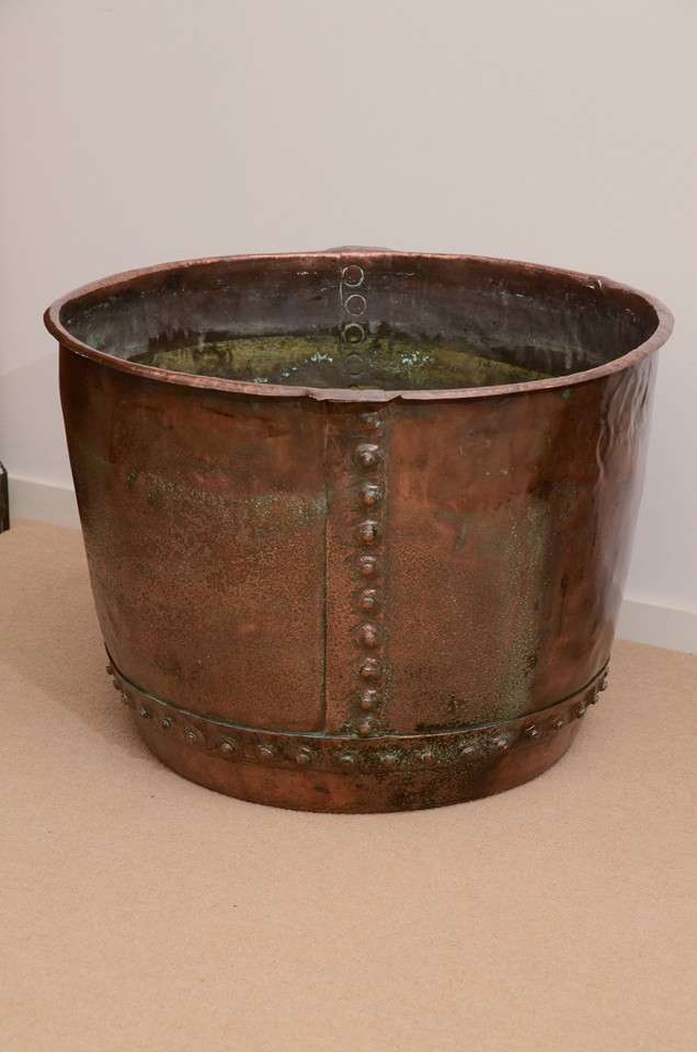 A large copper bucket with rivets on the side, carrying handles and a nicely aged patina.