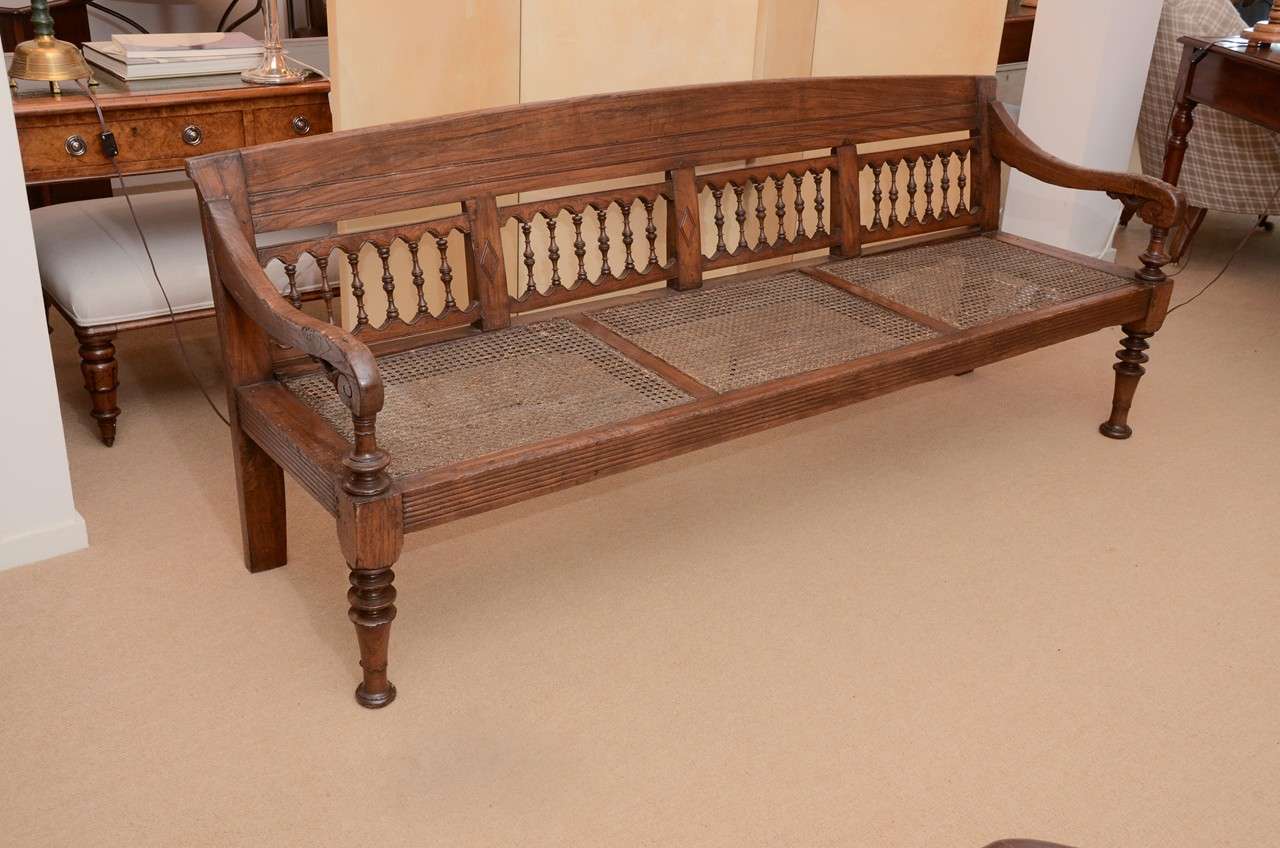 A long bobbin-rail bench with turned legs, arched back and scrolled arm. Comes with a new beige linen seat cushion.