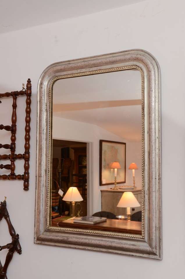 A silver giltwood mirror with leaf etching and antique mirror.